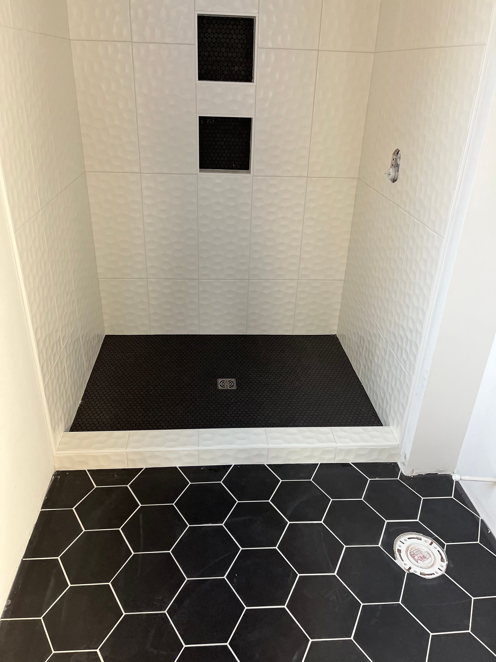 Shower remodel contractors | A black and white shower with a black tile floor
