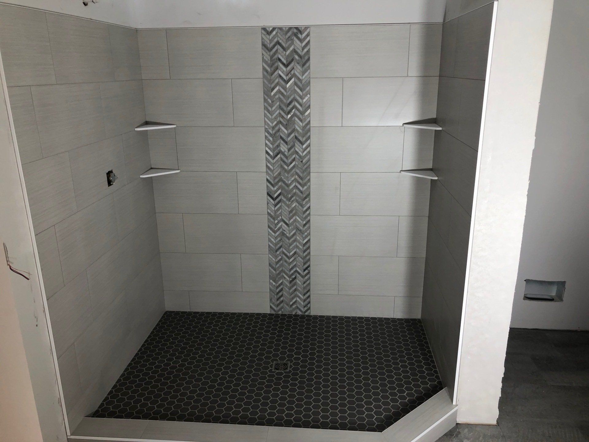 An accessible bathroom with a walk in shower with a chevron pattern on the wall.
