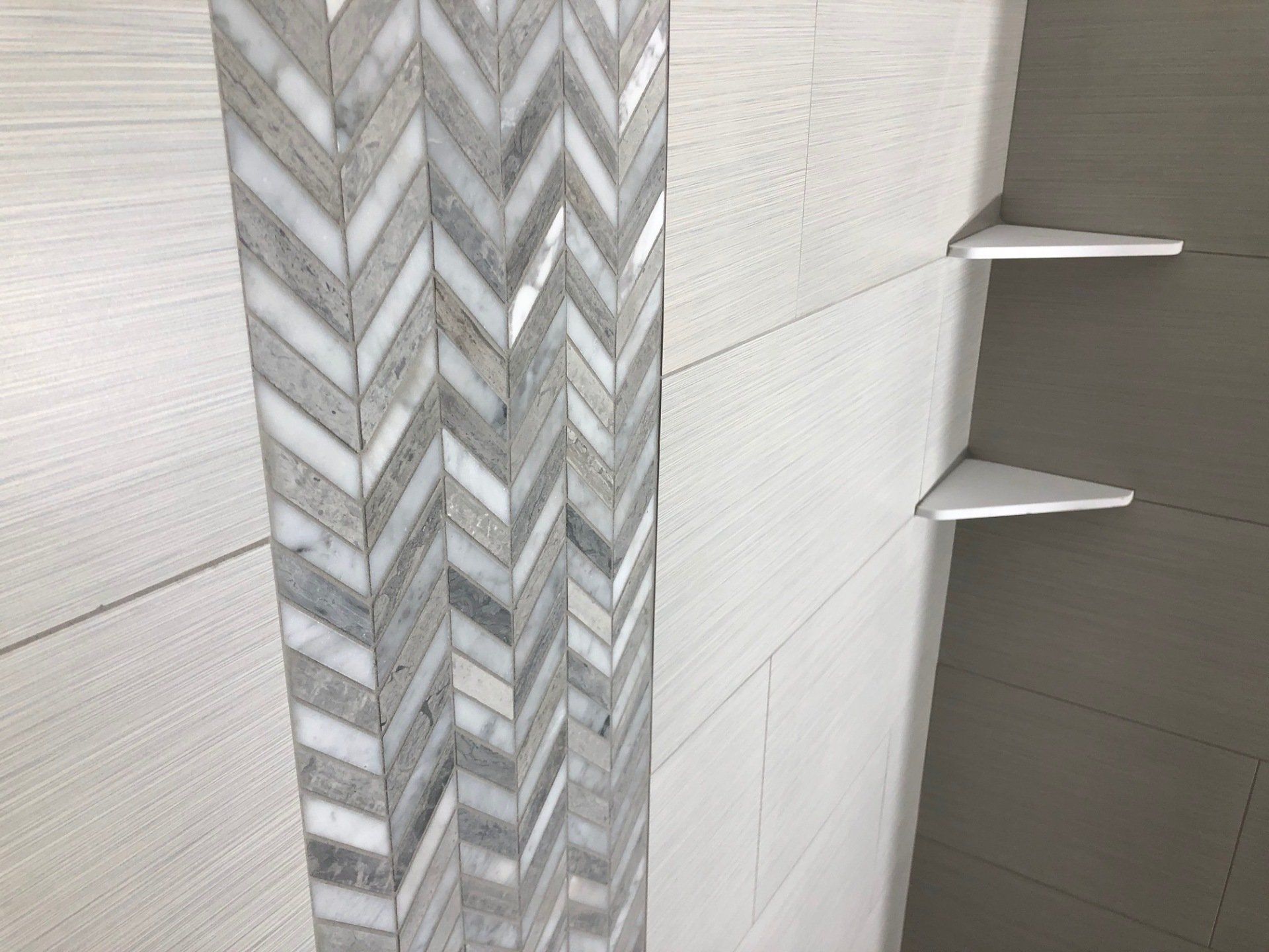 Redo shower walls | A shower with a chevron pattern on the wall and shelves.