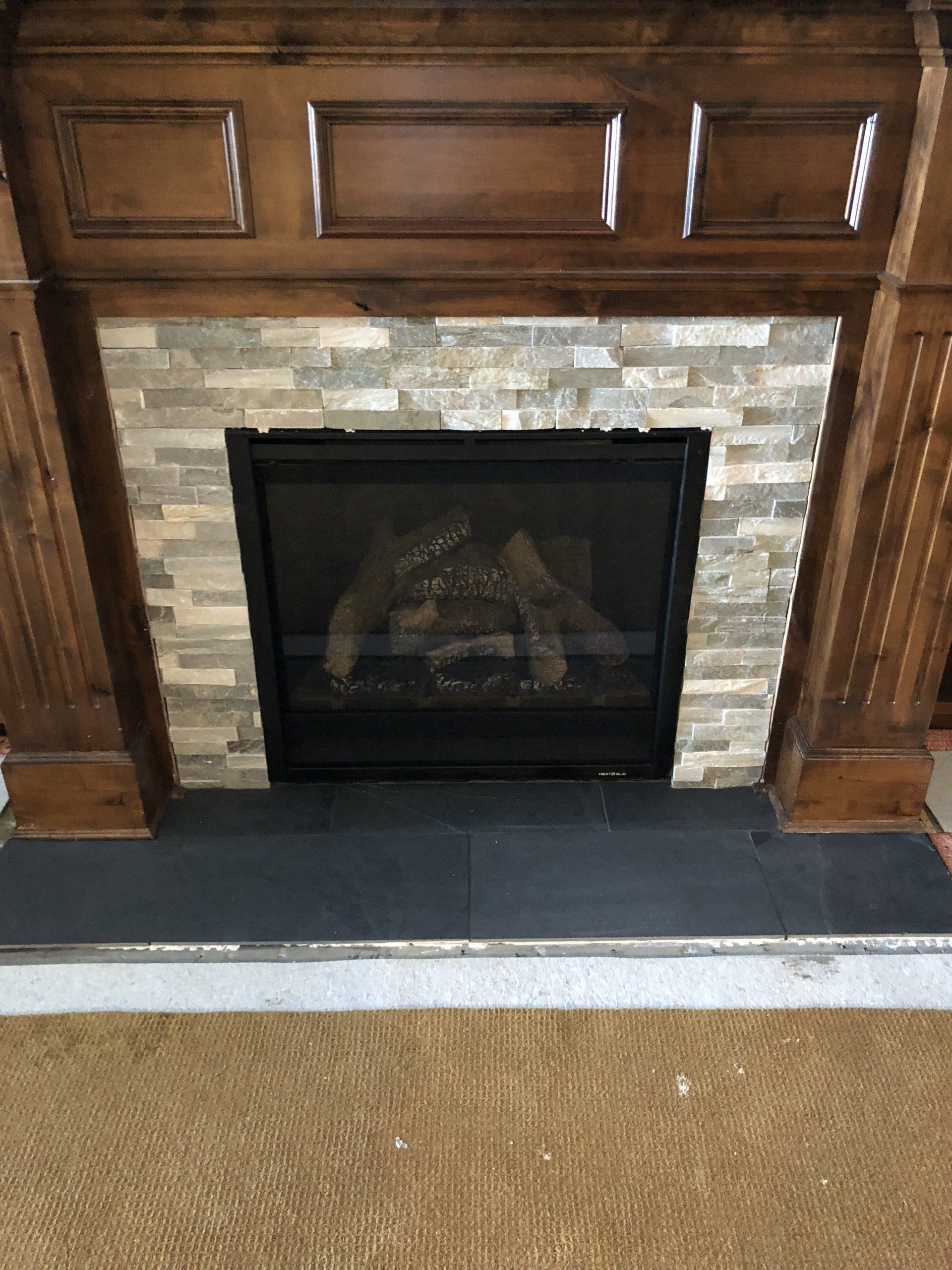 A fireplace with a brick wall and a wooden mantle in a living room.