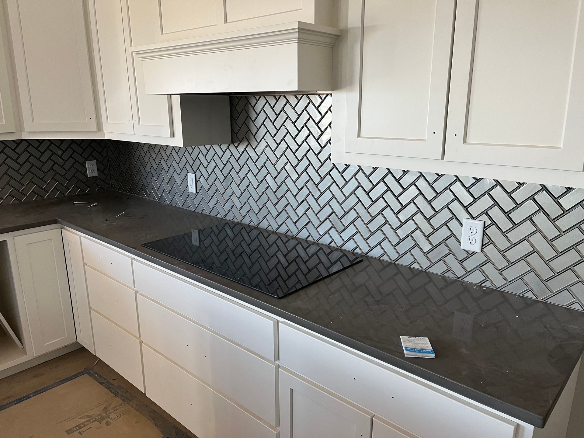 Kitchen remodelingA kitchen with white cabinets and a black stove top oven.