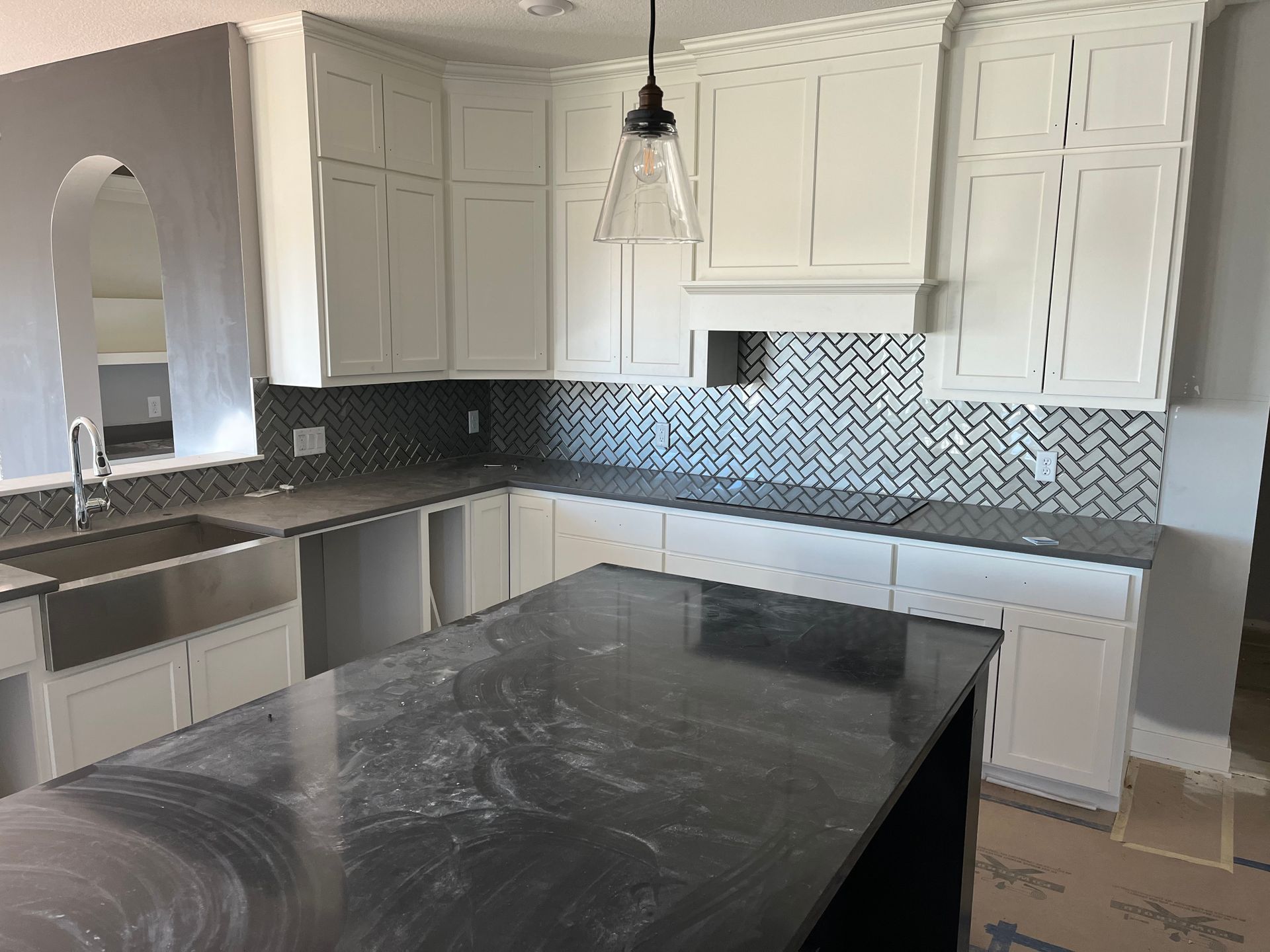 Kitchen and bath remodeling | A kitchen with white cabinets , black counter tops , a sink , and a large island.