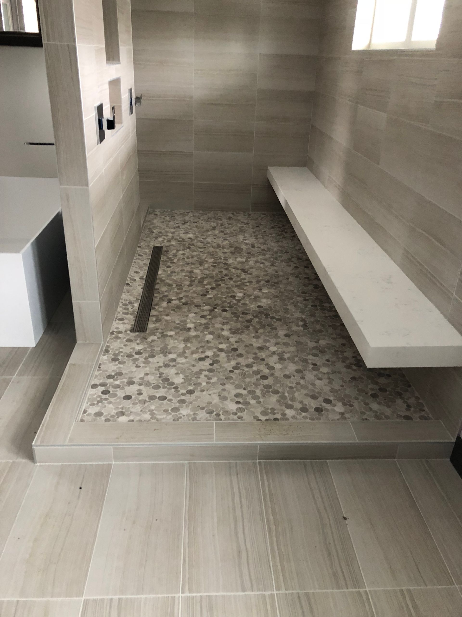 A bathroom with a walk in shower and a bench.