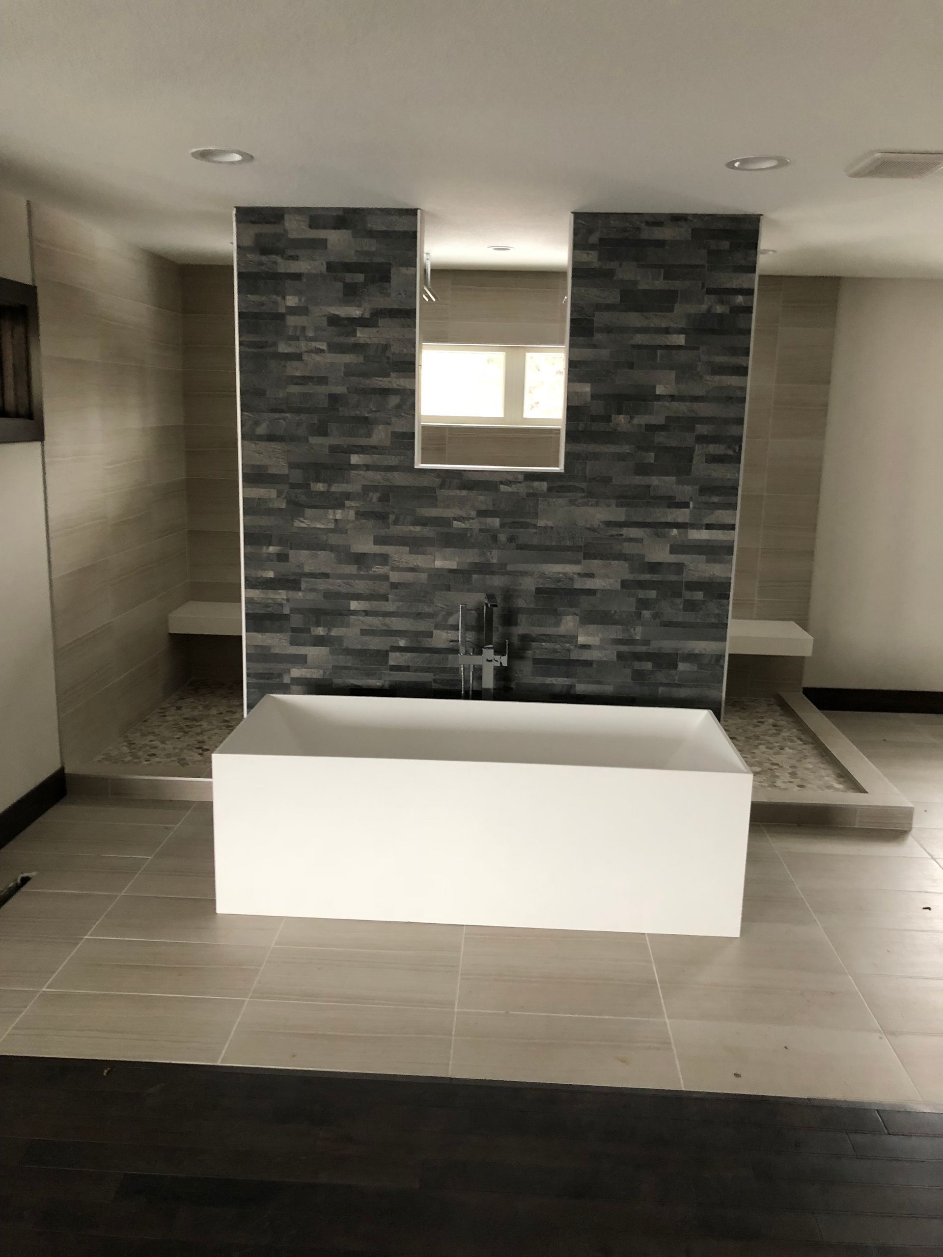 A renovated bathroom with a bathtub and a stone wall