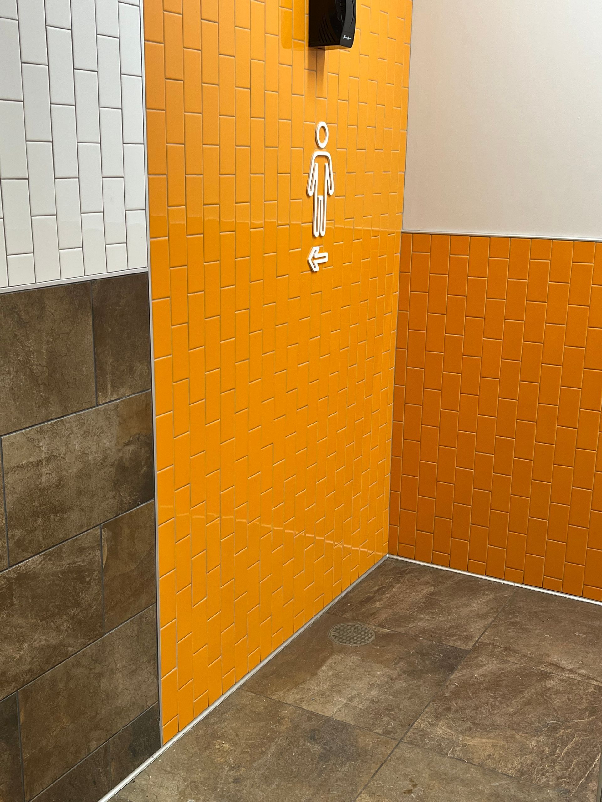 A commercial bathroom with orange tiles and a sign that says ' a ' on it