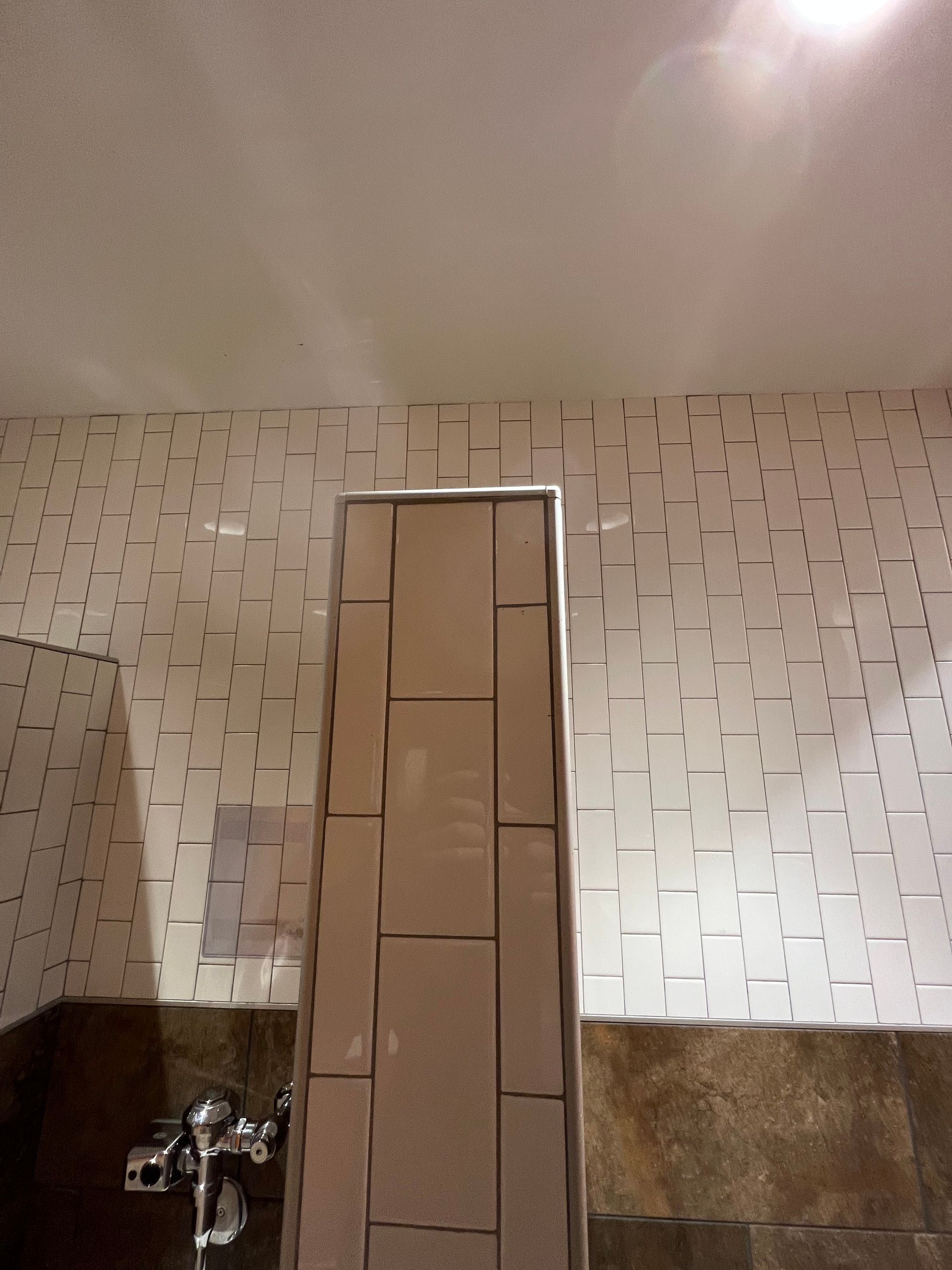 A bathroom with white tiles and a toilet