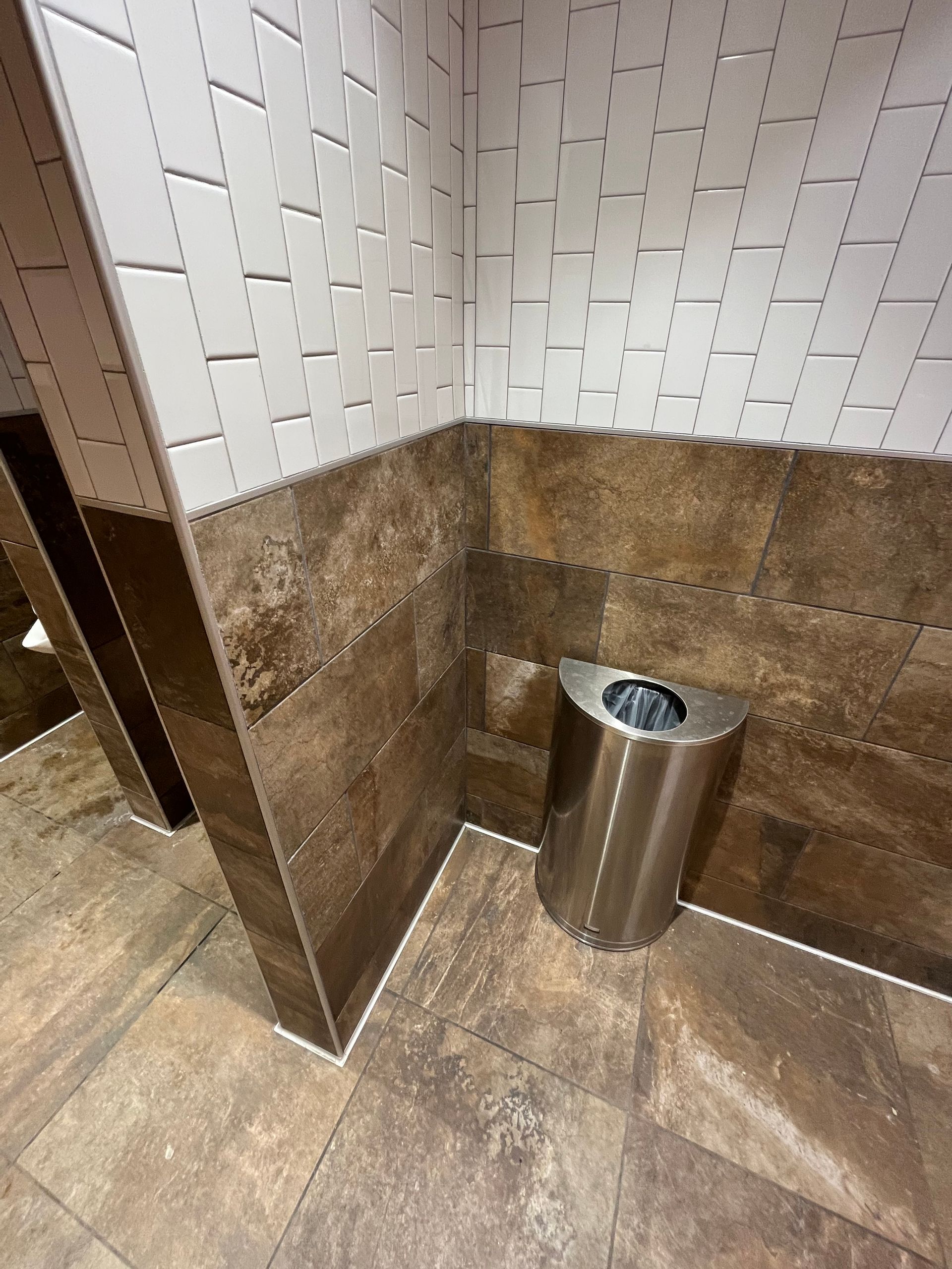 Commercial tiling contractors work | BYN the Tile Crew | A stainless steel trash can is in the corner of a bathroom.