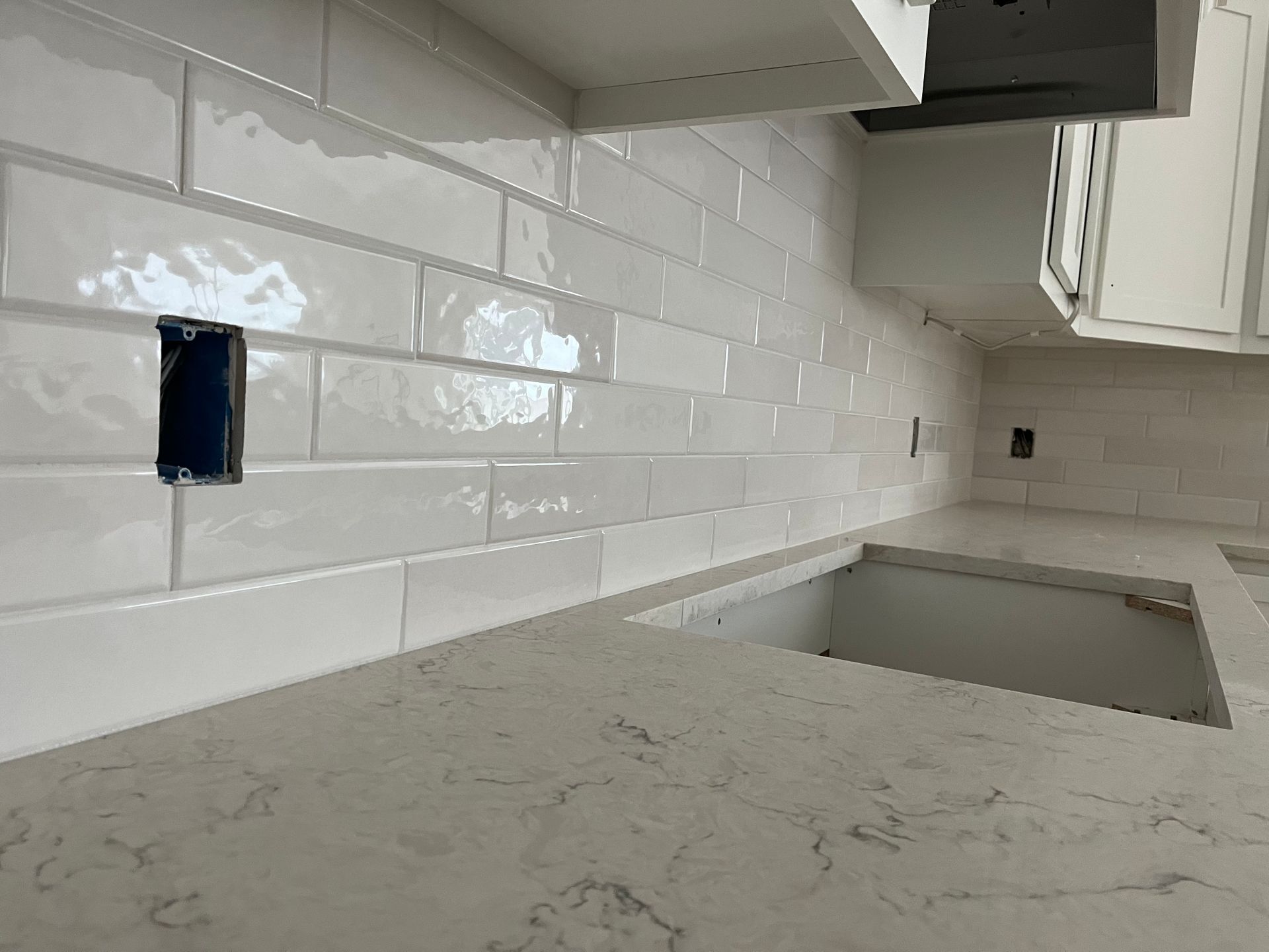 A kitchen with white subway tiles and a white counter top.