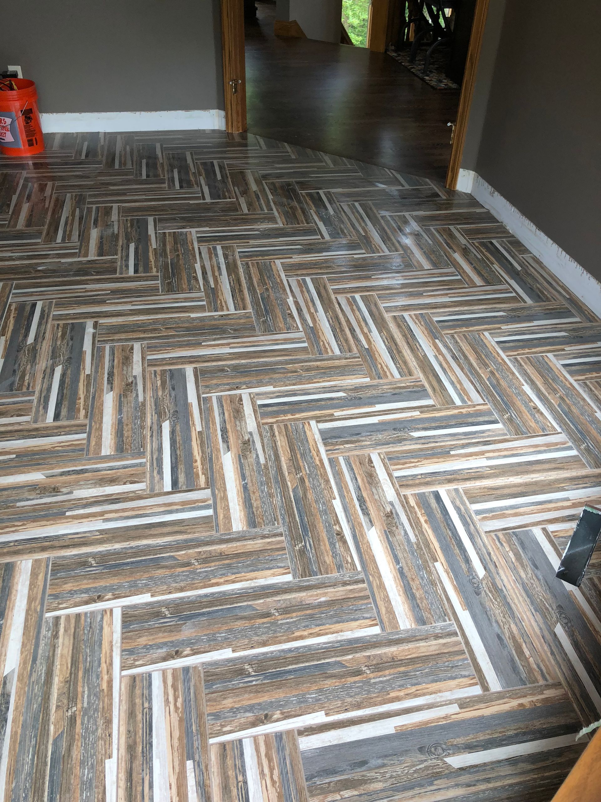 A wooden floor with a herringbone pattern in a room.