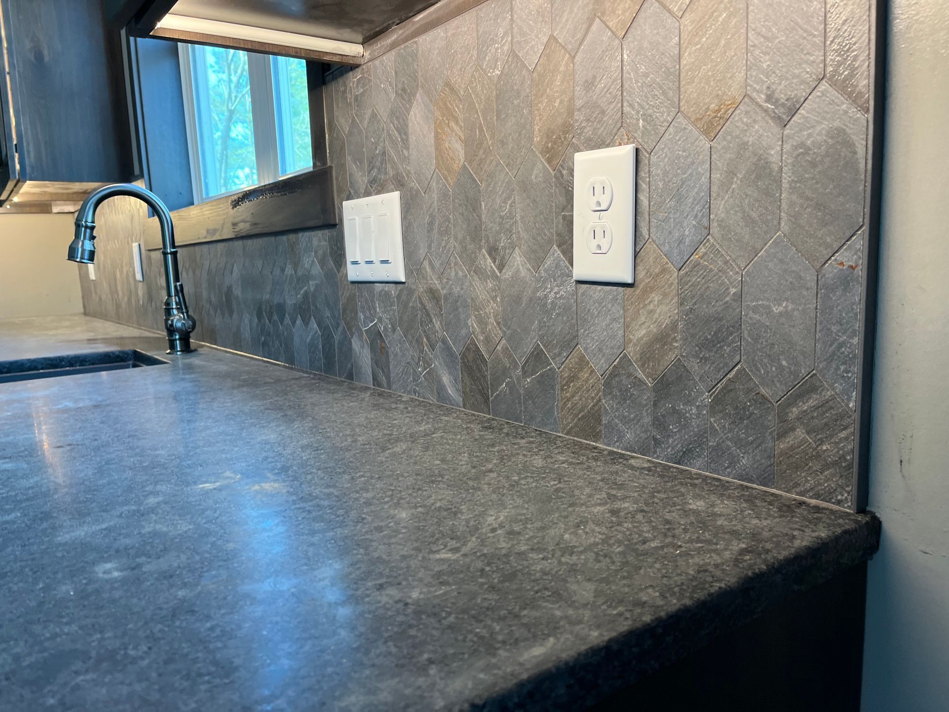Kitchen backsplash, a counter with a sink, faucet and electrical outlets.