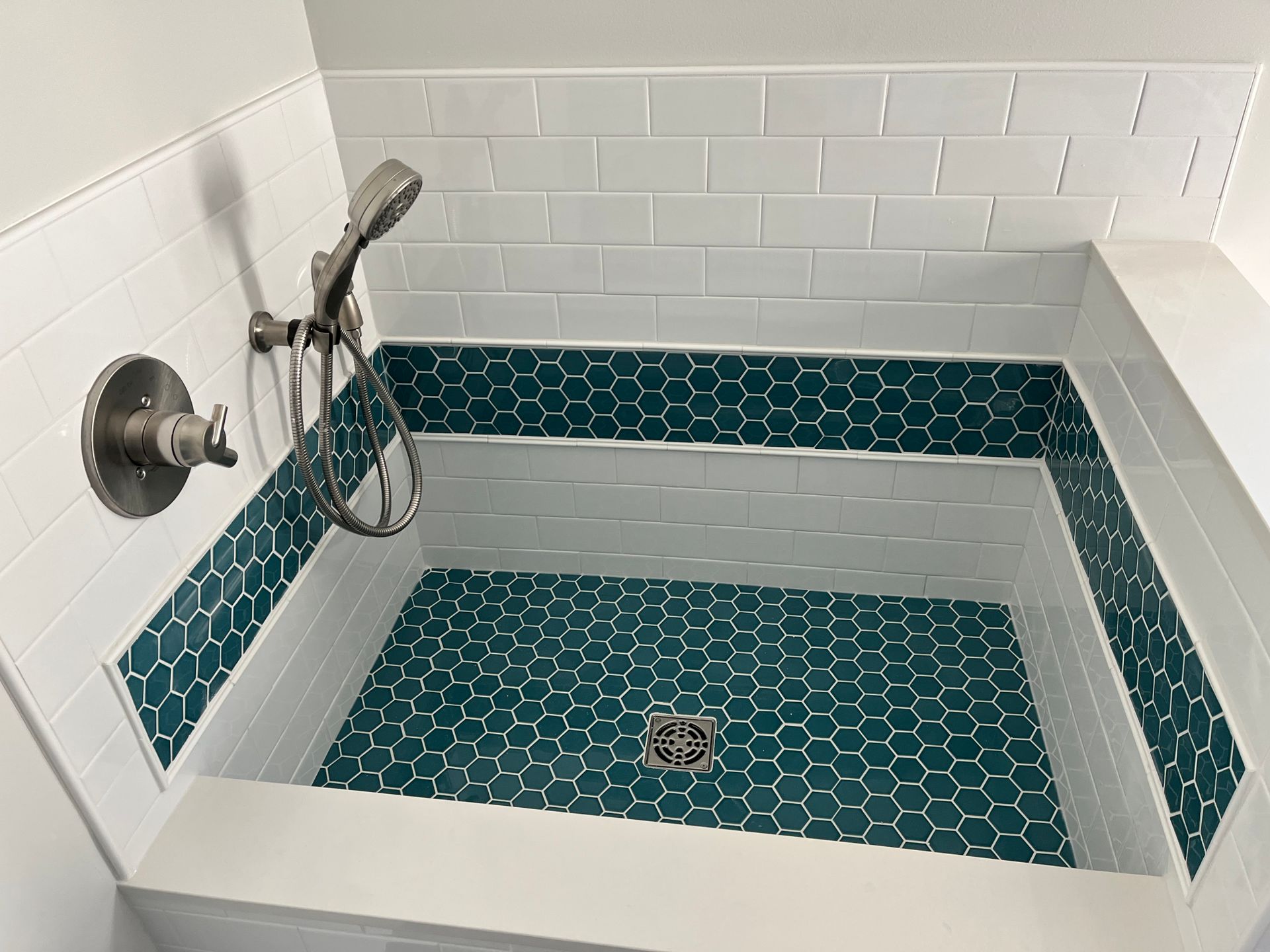 Shower to bathtub conversion | A shower with a blue tile floor and a shower head
