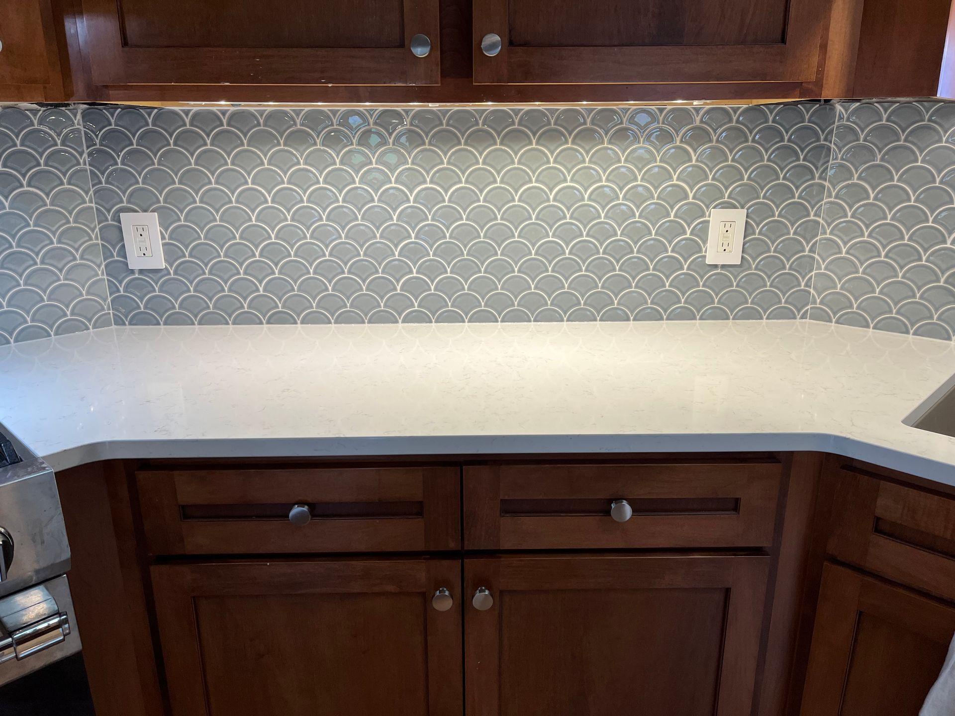 A kitchen backsplash with wooden cabinets and a white counter top.