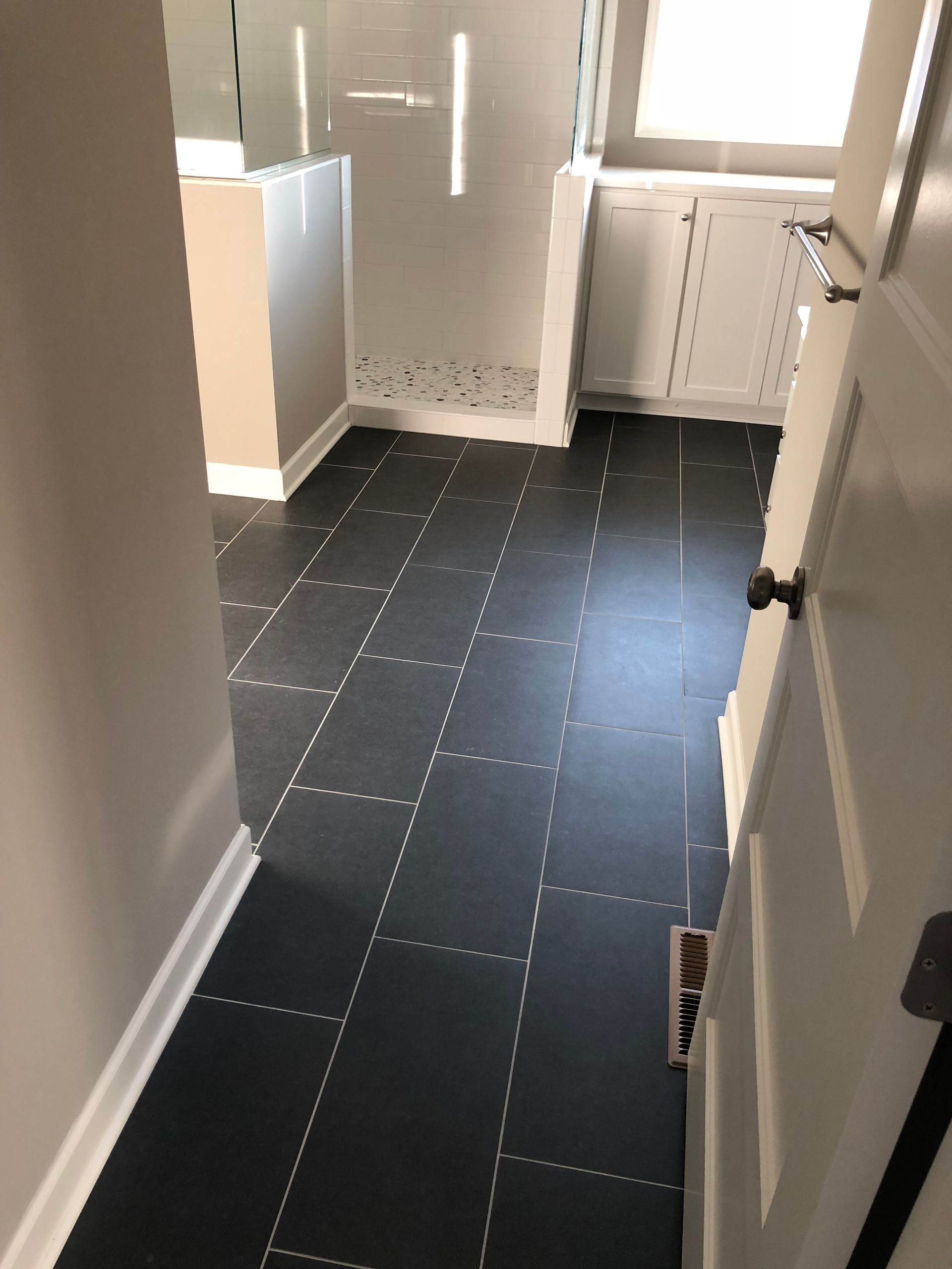A bathroom with a black tile floor and white cabinets