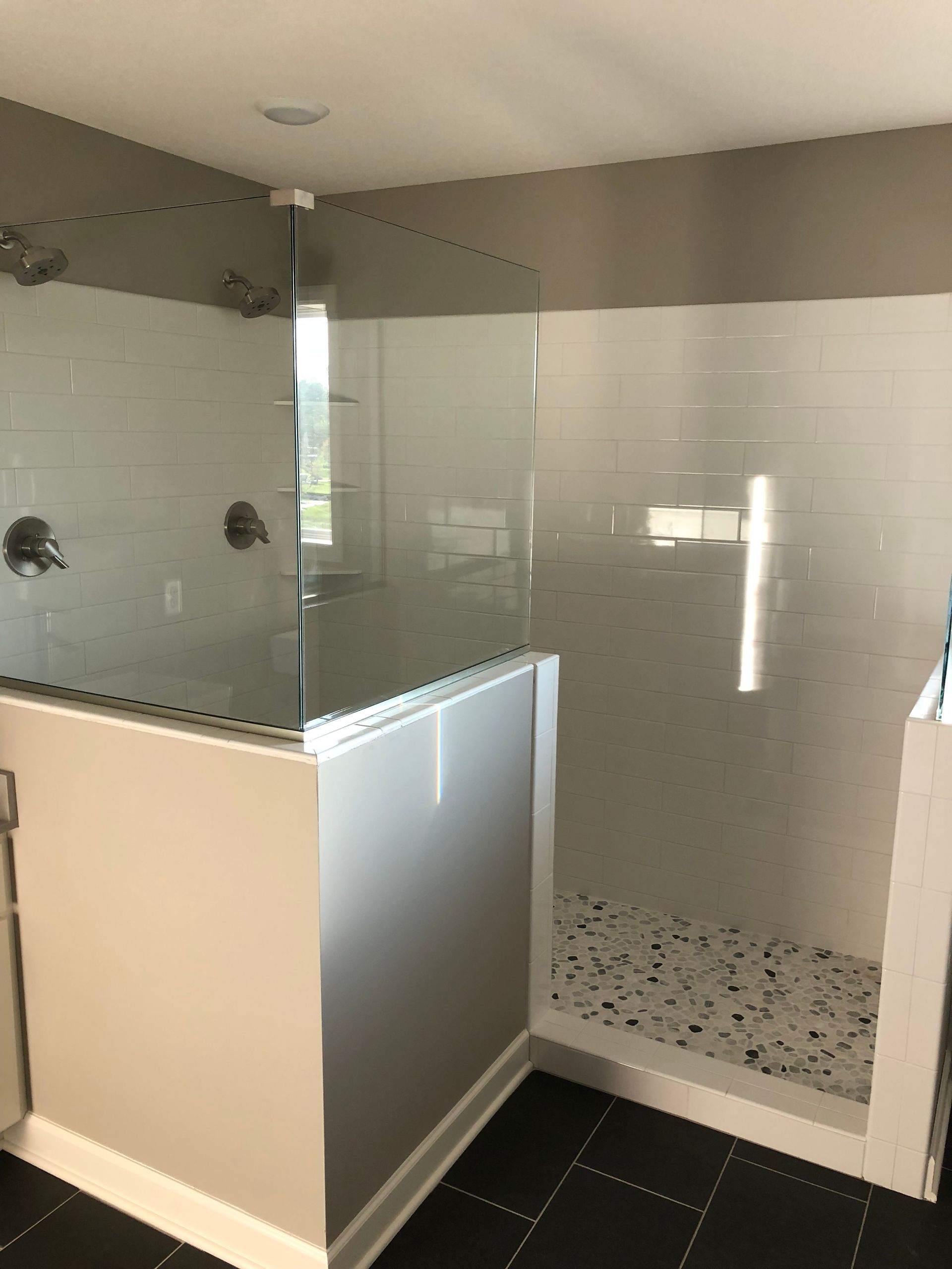 A bathroom with a walk in shower with a glass door.