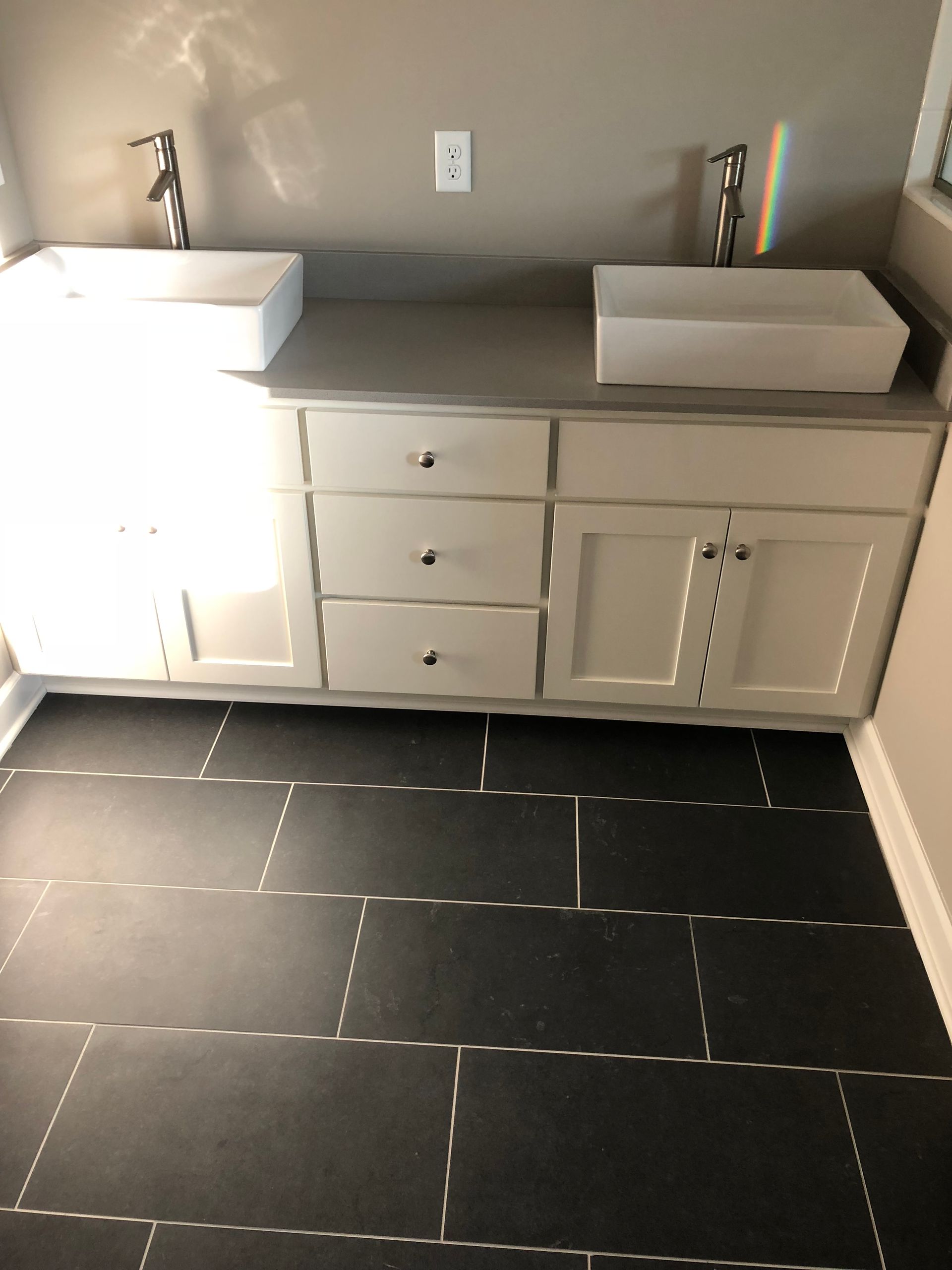 A bathroom with two sinks and a black tile floor