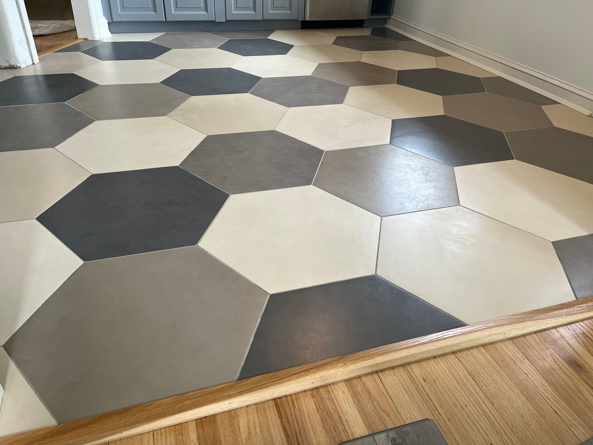 A kitchen with a hexagonal tile floor and a wooden floor.