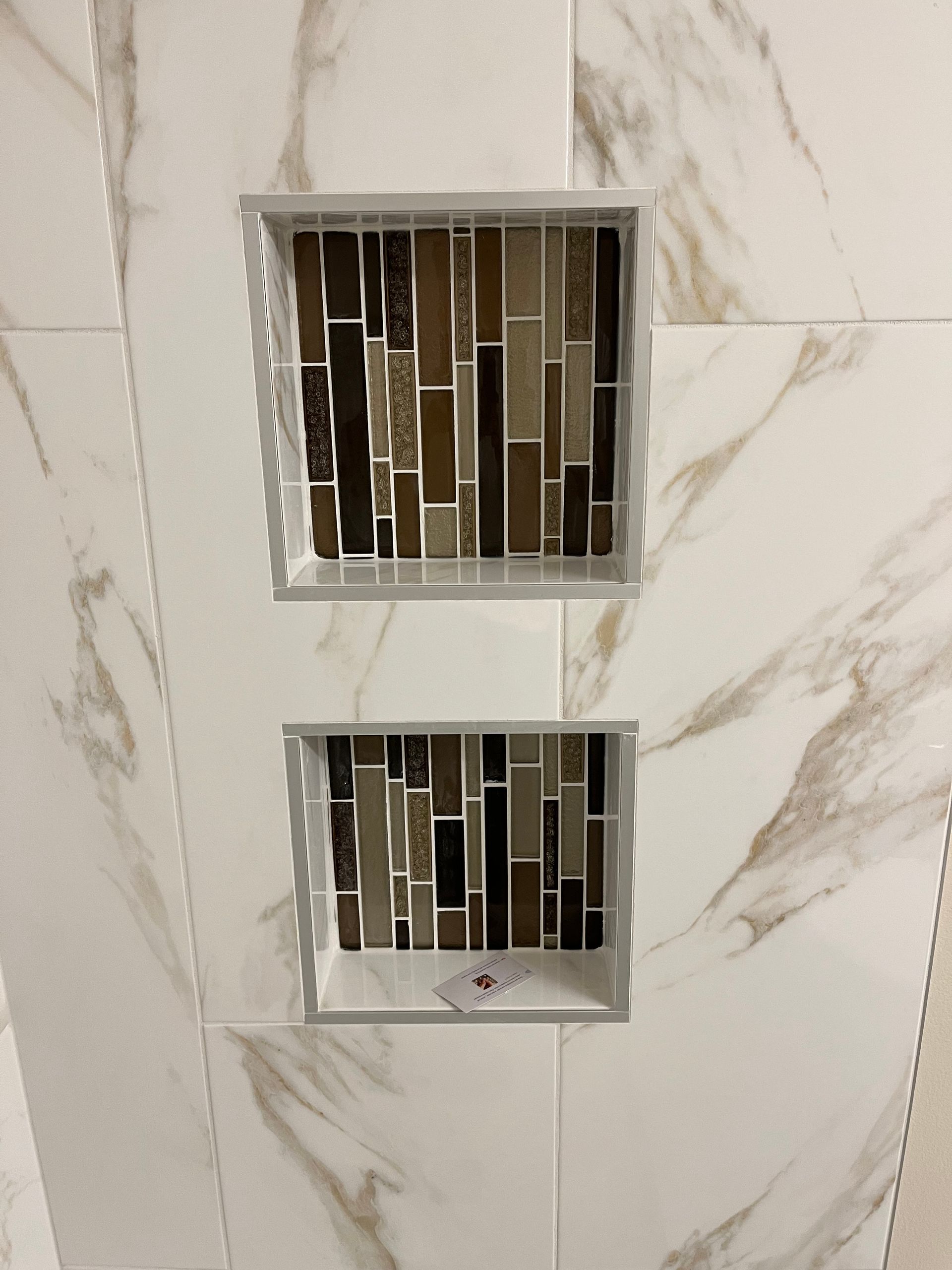 A bathroom with two shower niches built into the wall.