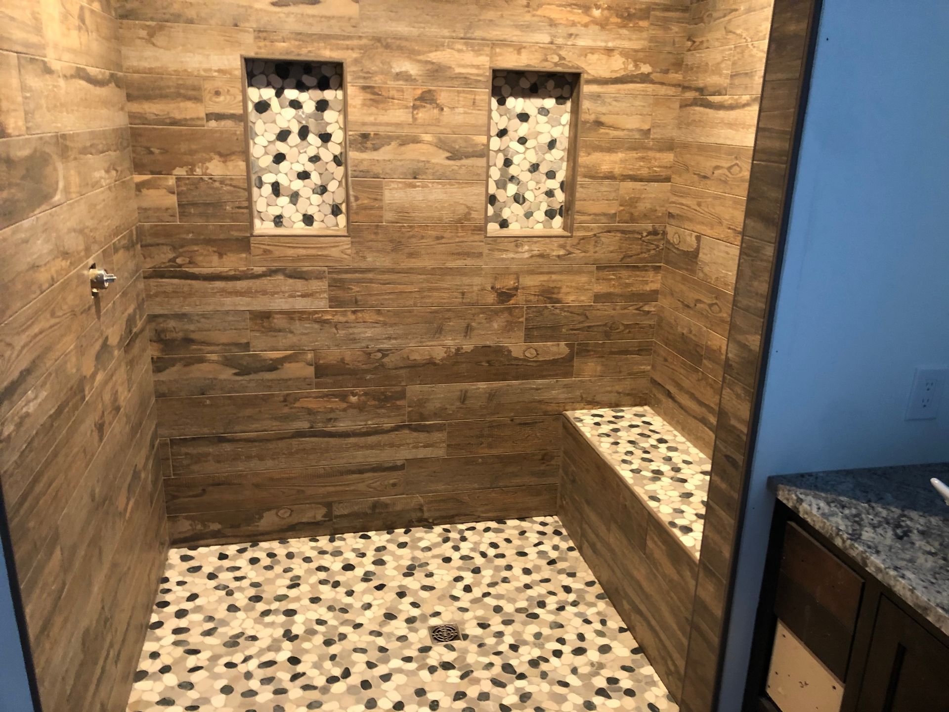 A bathroom with a walk in shower and a bench | BYN the Tile Crew