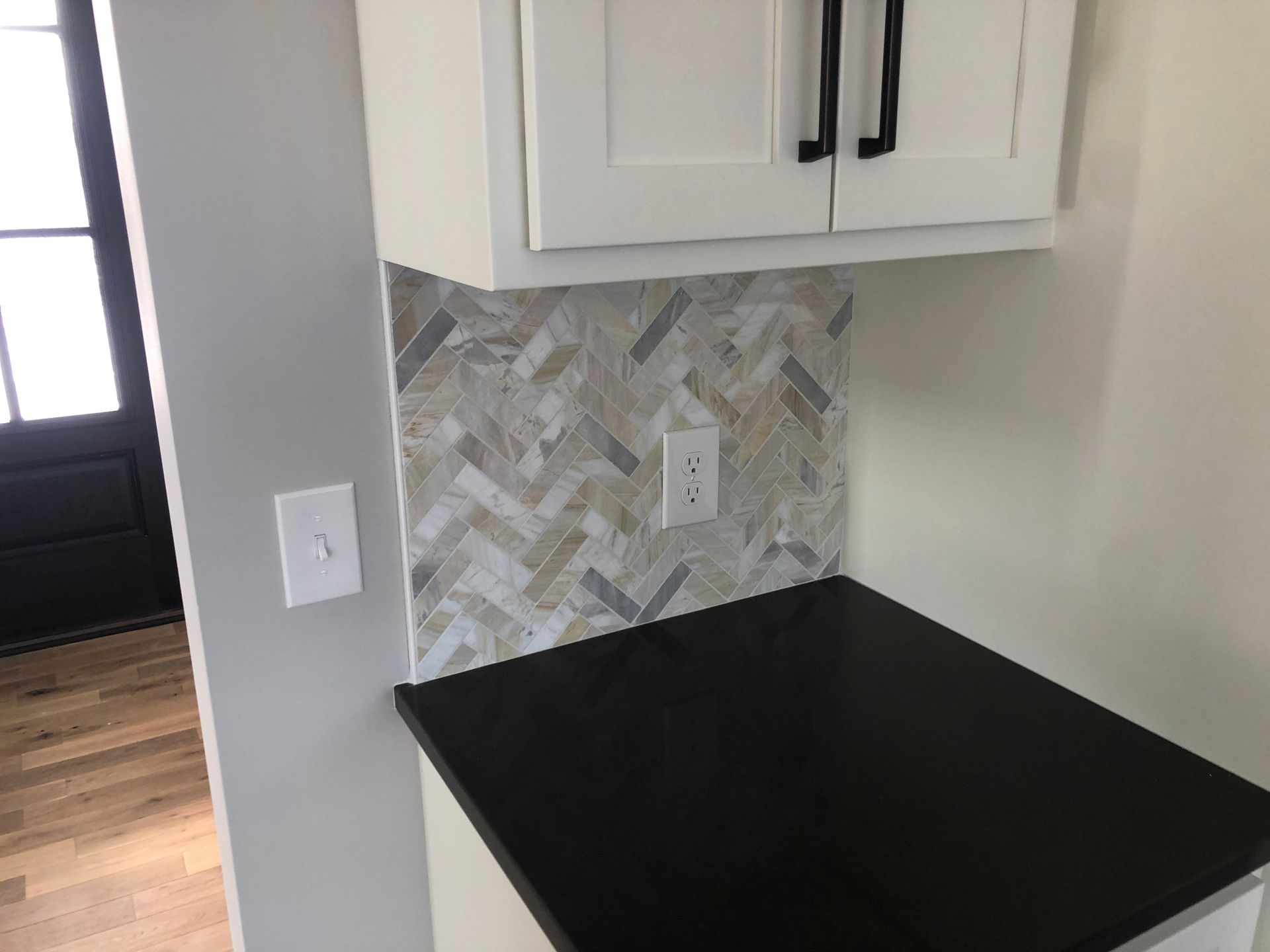 A kitchen backsplash with white cabinets and a black counter top.