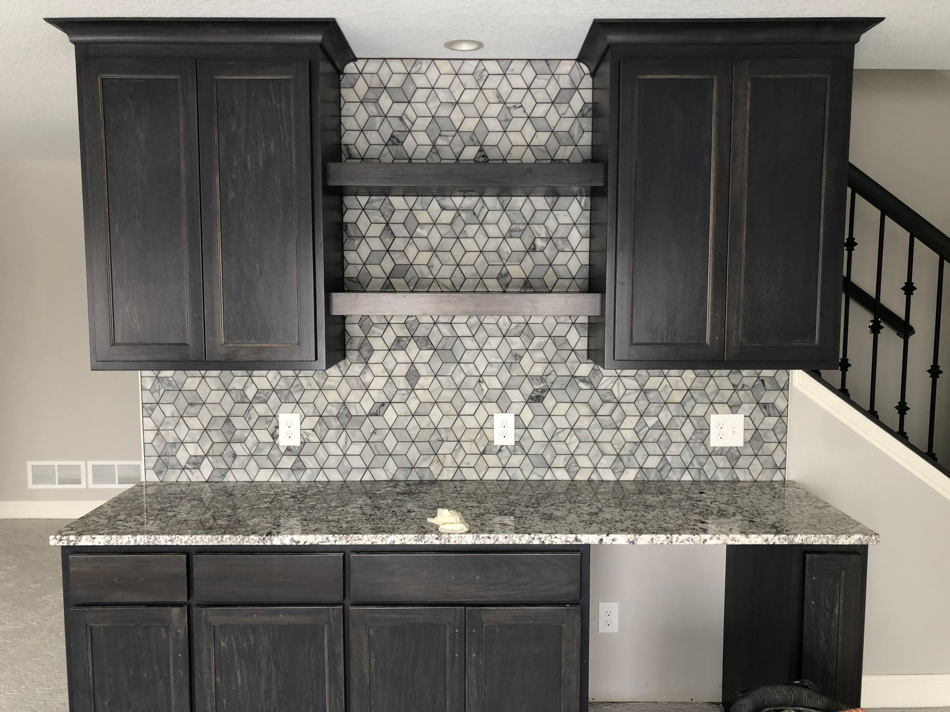 A kitchen remodel with black cabinets and granite counter tops