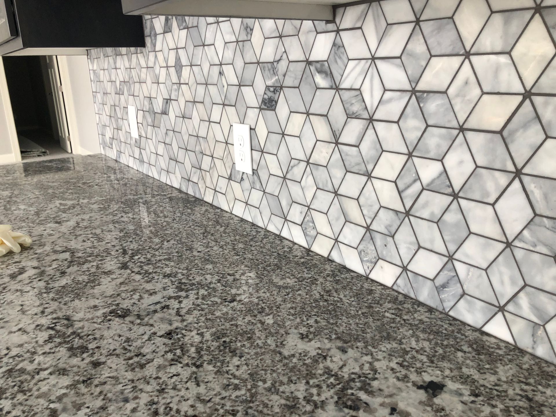 A kitchen redo with a marble counter top and a marble wall.