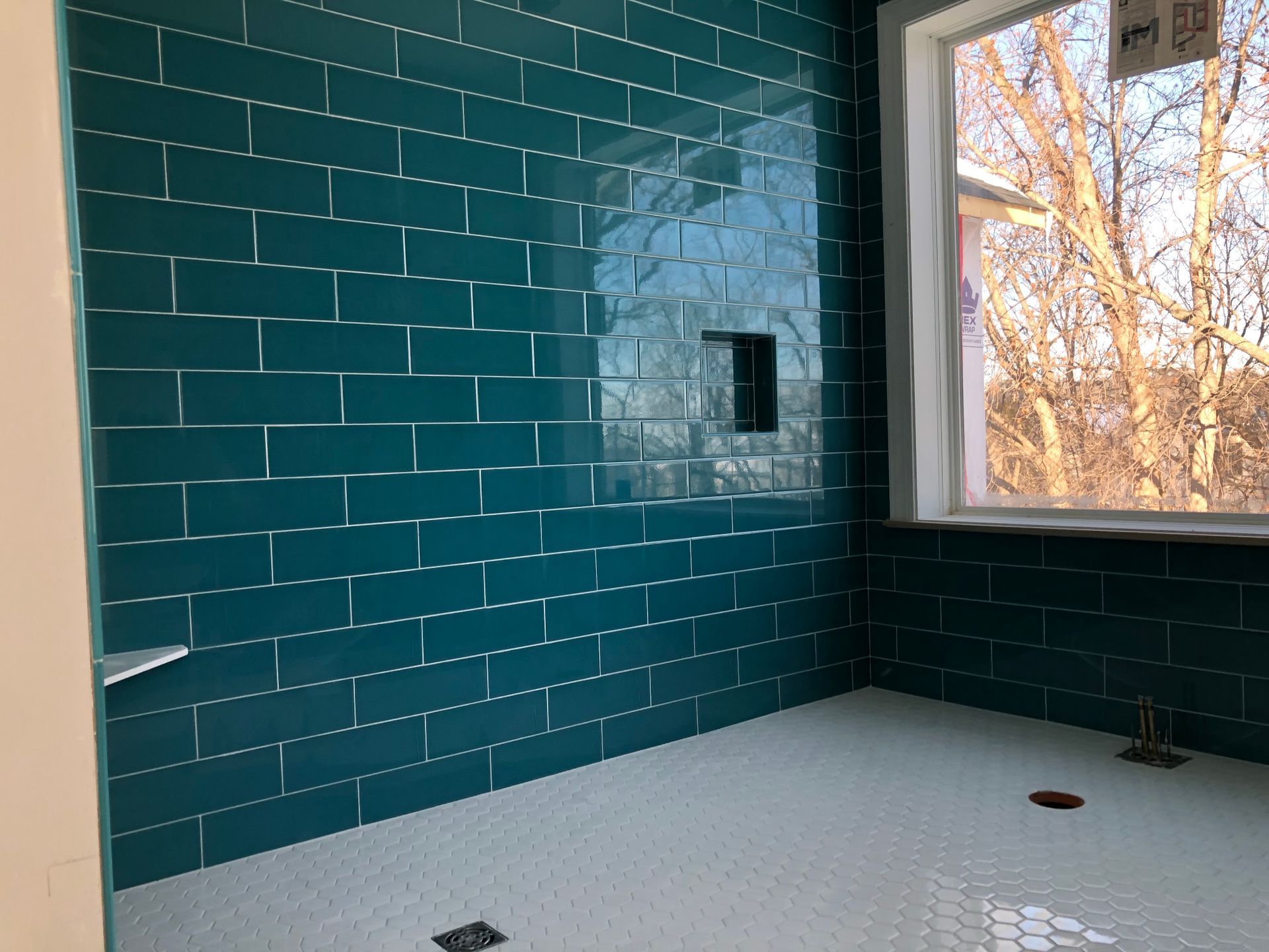Bathroom remodel with tile walls | A bathroom with blue tiles and a window.