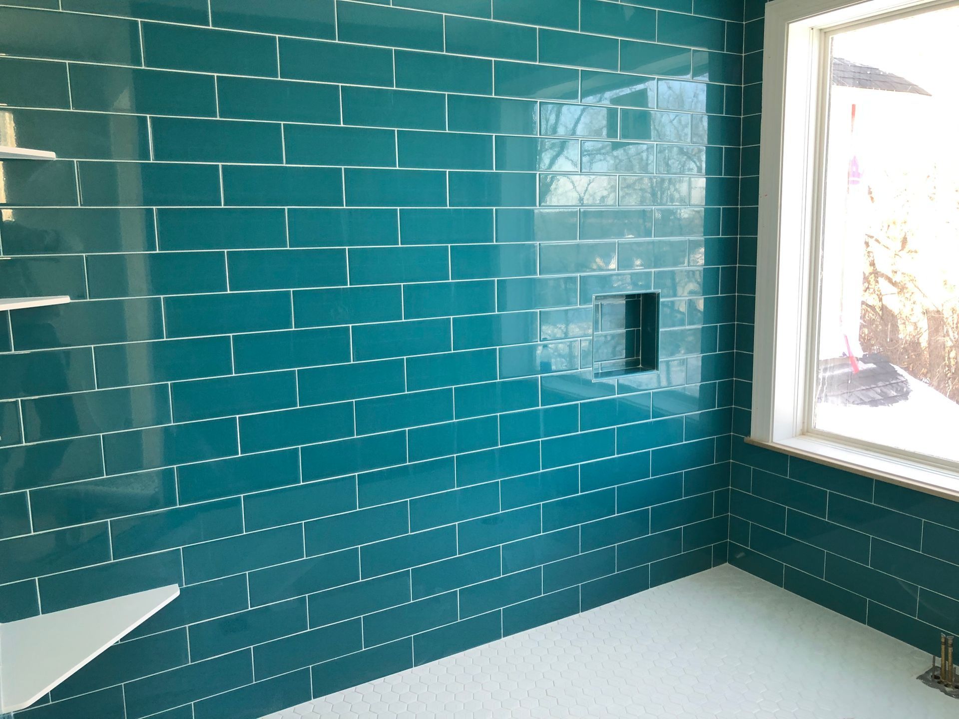 Bathroom remodel with tile walls | A bathroom with blue tiles and a window