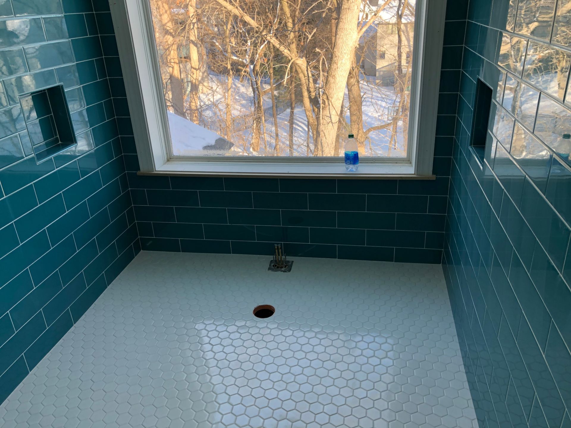Bath and shower remodel | A bathroom with blue tiles and a window with trees in the background