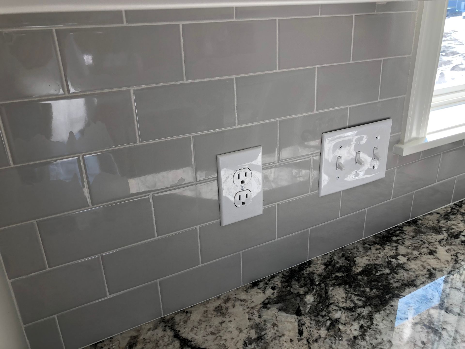 A kitchen with a subway tile backsplash and granite counter tops.