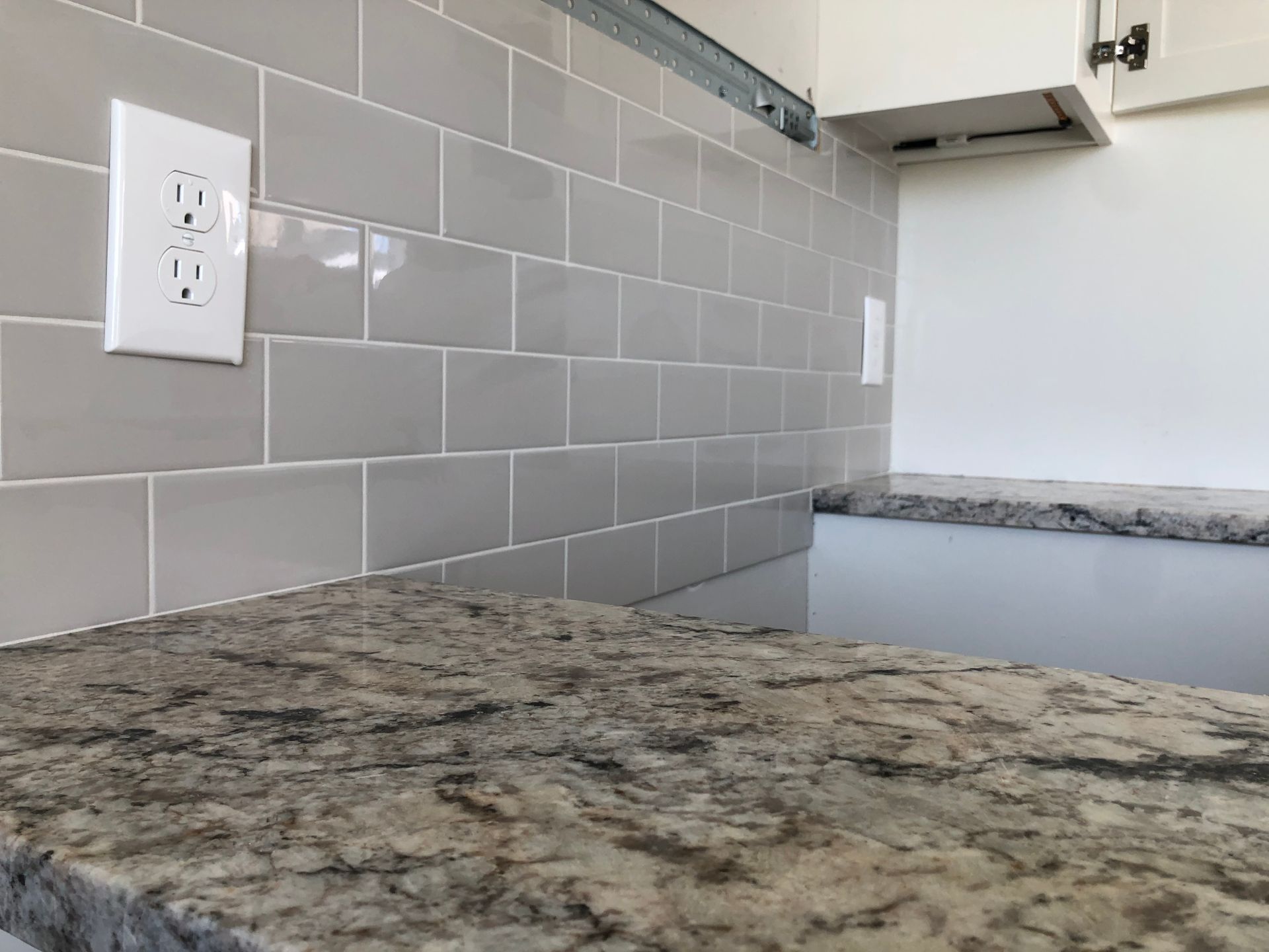 A kitchen with a granite counter top and a subway tile backsplash.