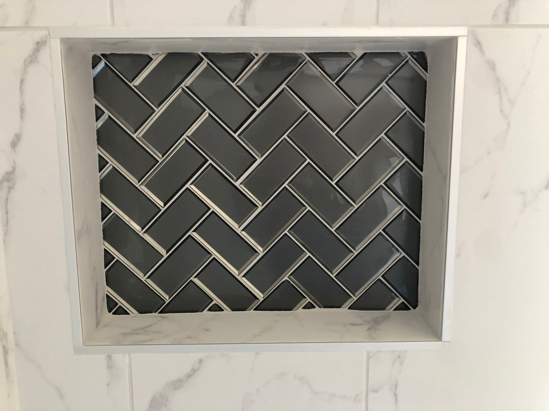 A shower niche with a herringbone pattern on it.