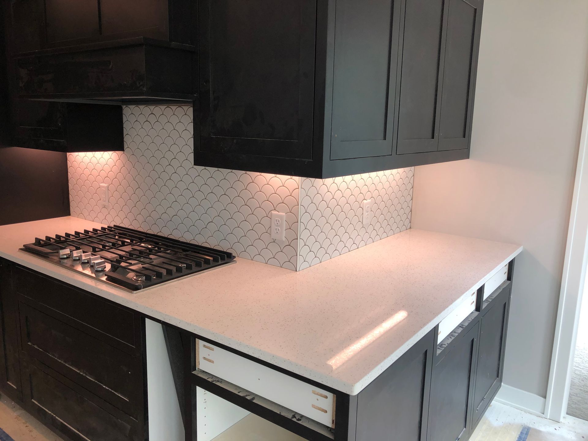 A remodeled kitchen with black cabinets and white counter tops