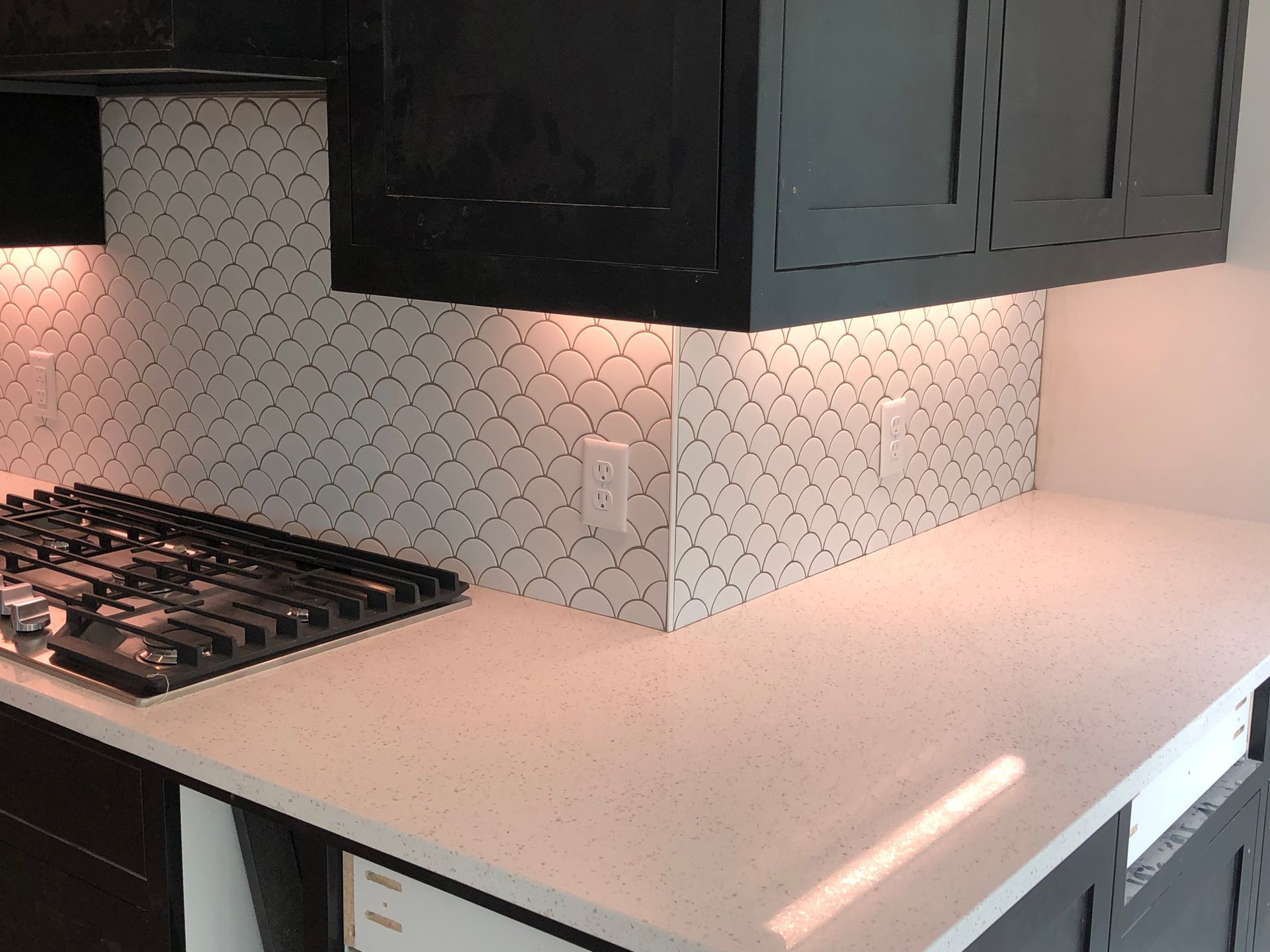 Backsplash | A kitchen with a stove top oven and black cabinets