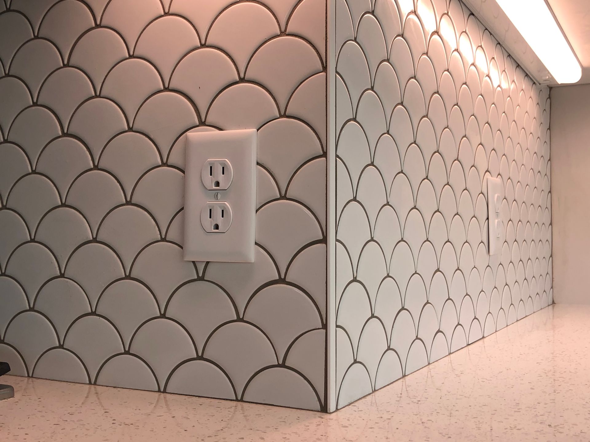 A corner of a kitchen with a fish scale pattern on the backsplash