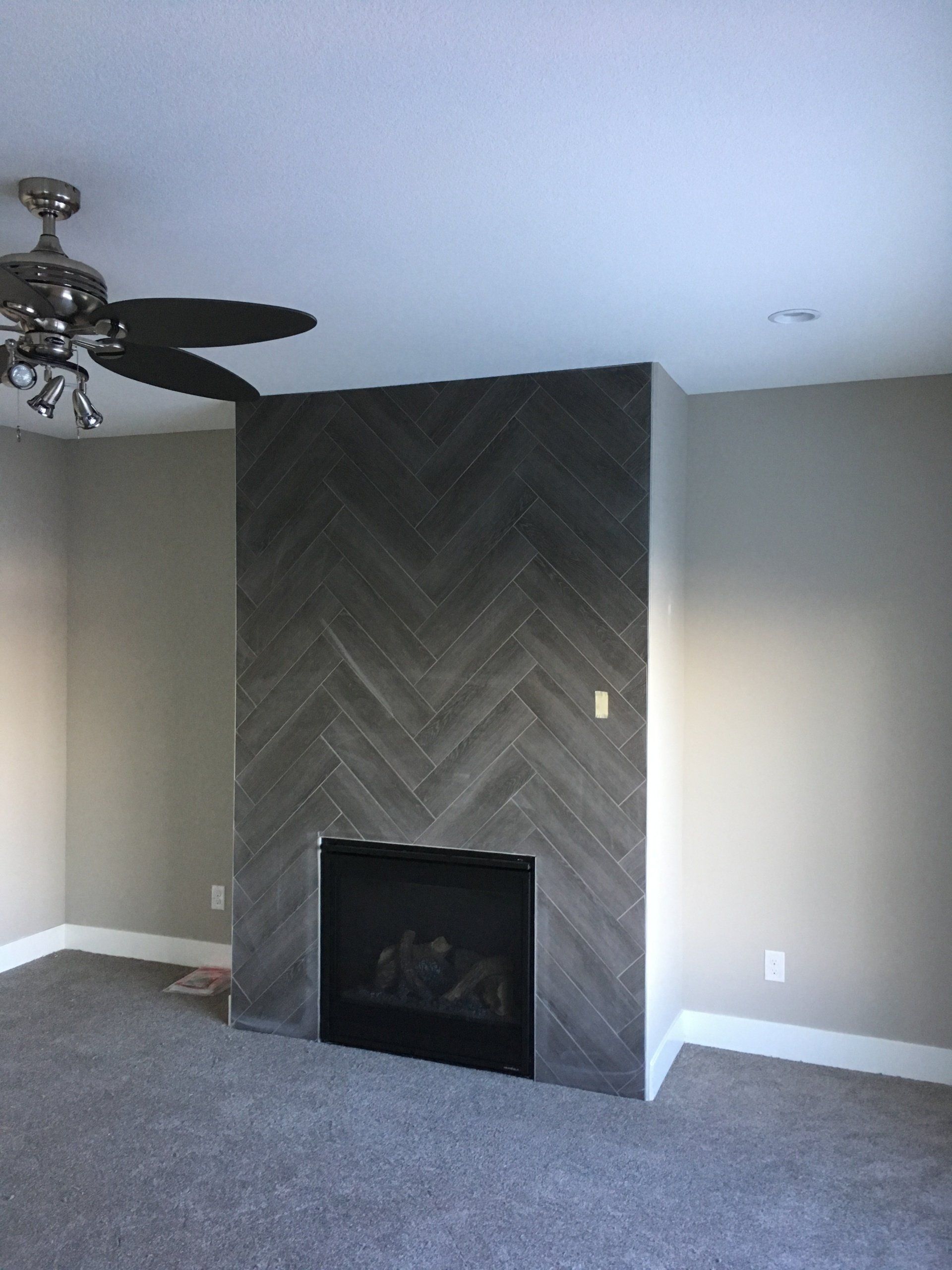 A living room with a fireplace and a ceiling fan