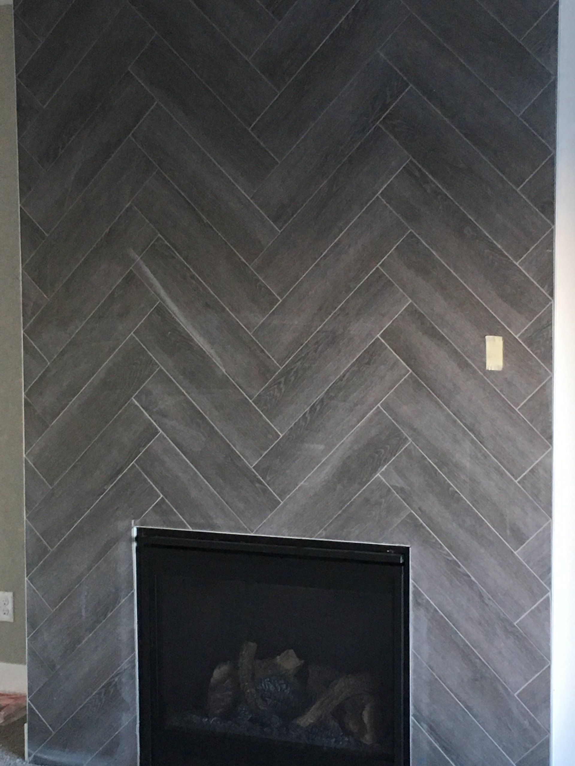 A fireplace with a herringbone pattern on the wall.