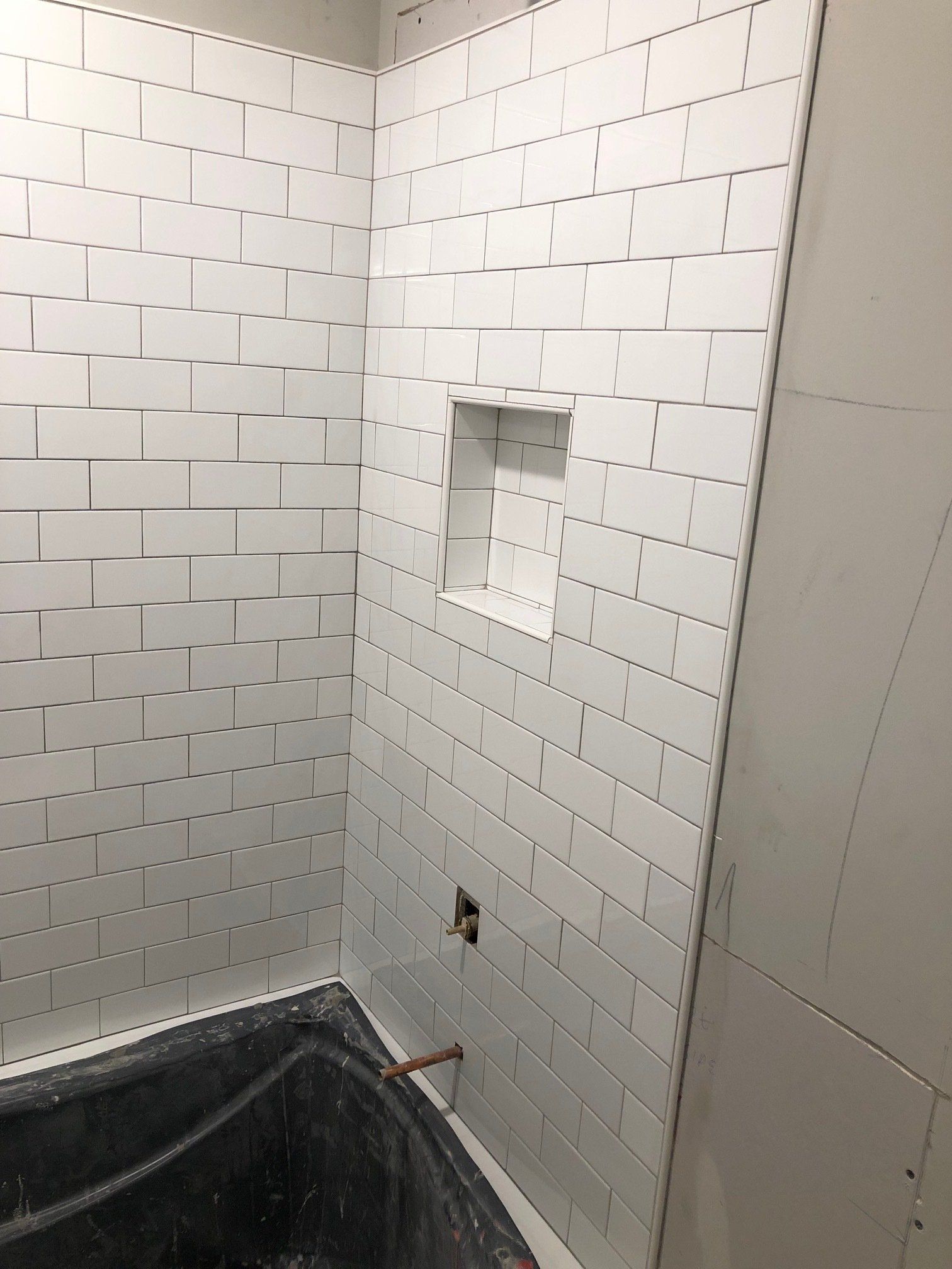 A bathroom with white brick walls and a bathtub.