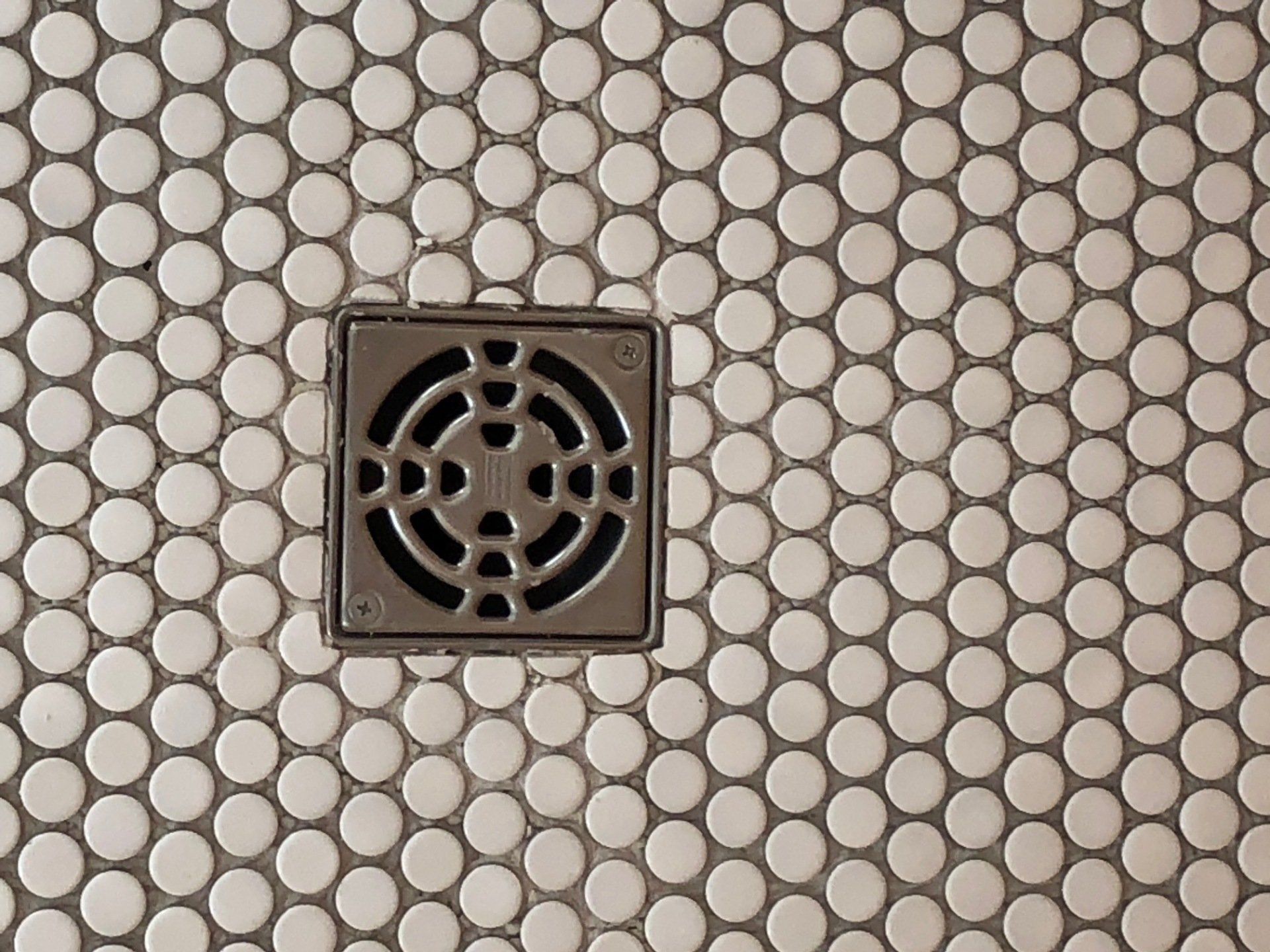 A close up of a drain on a tiled floor