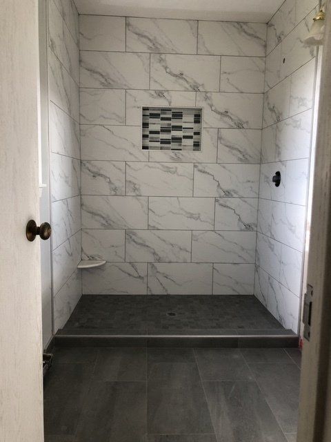 Shower bath remodeling | A bathroom with marble tiles and a walk in shower.