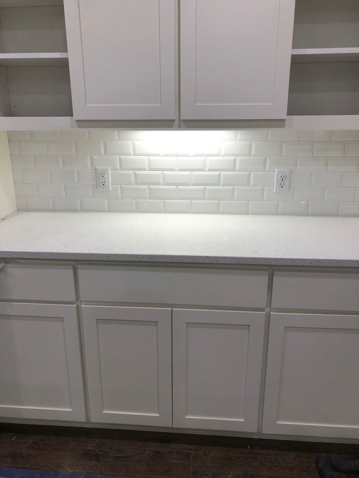 Backsplash work | A kitchen with white cabinets and a white counter top.