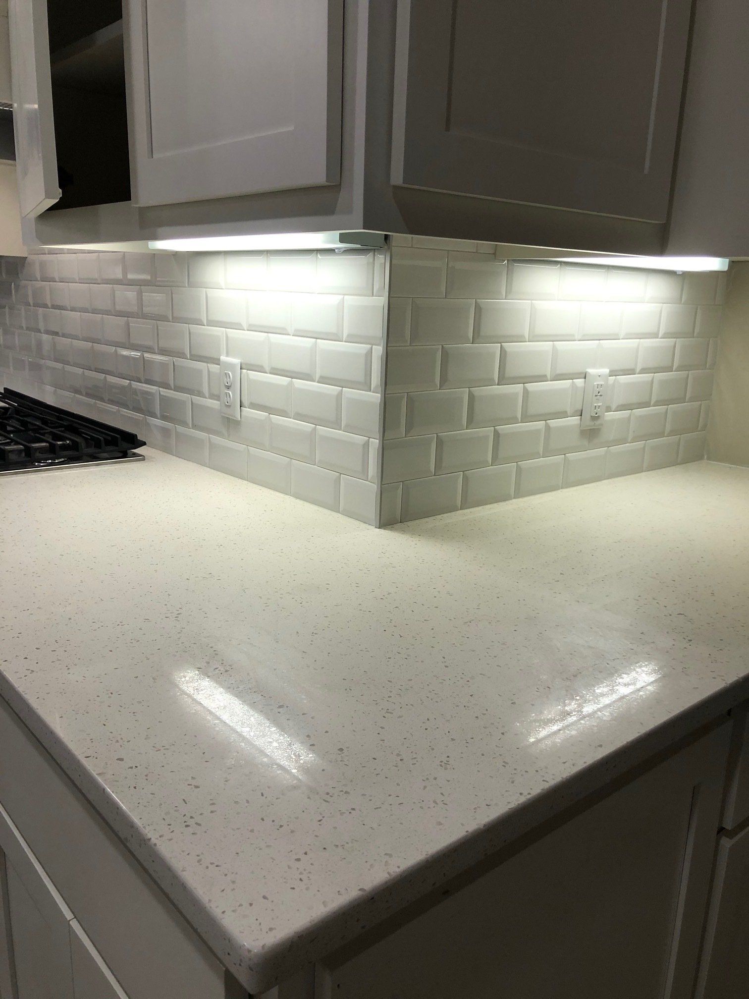 A kitchen with white cabinets , white counter tops , and a stove top oven.