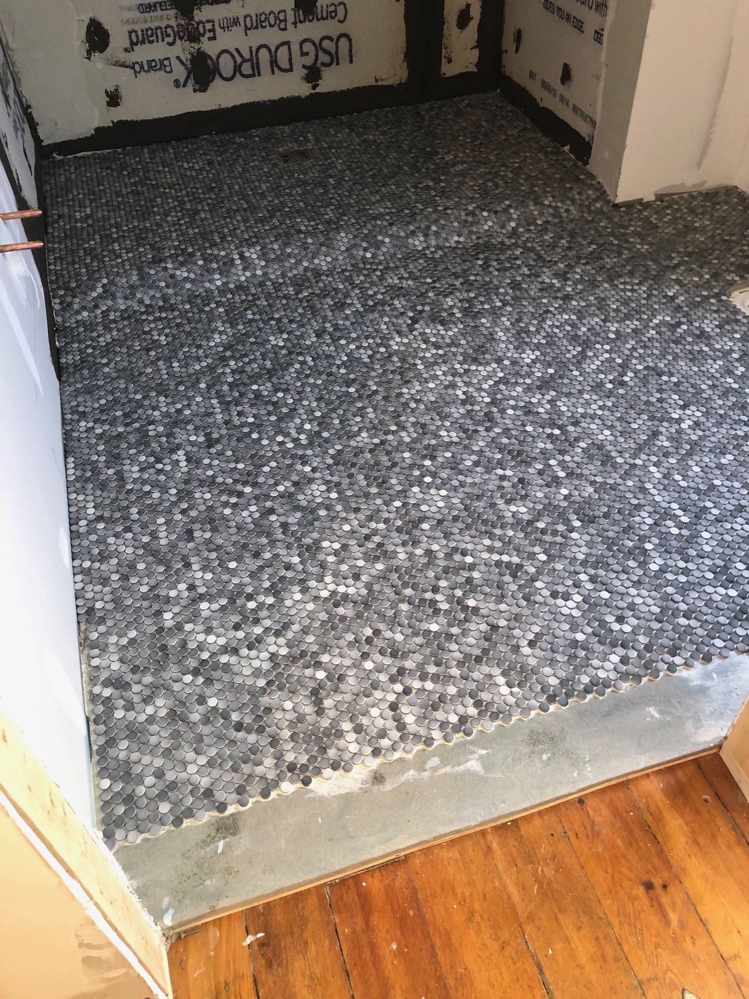 A room with a wooden floor and a gray tile floor.