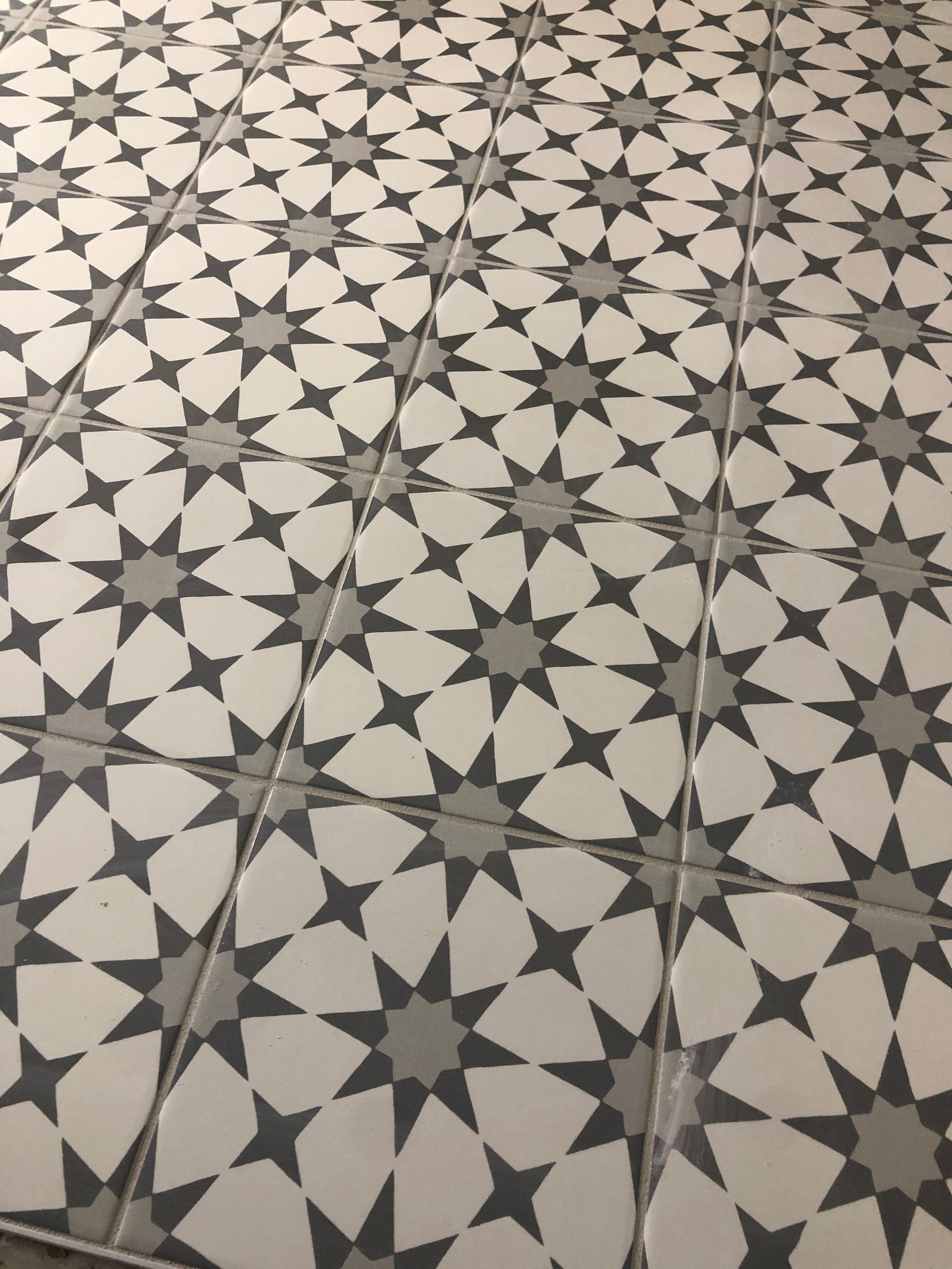 Ceramic tile flooring | A black and white tile floor with a star pattern