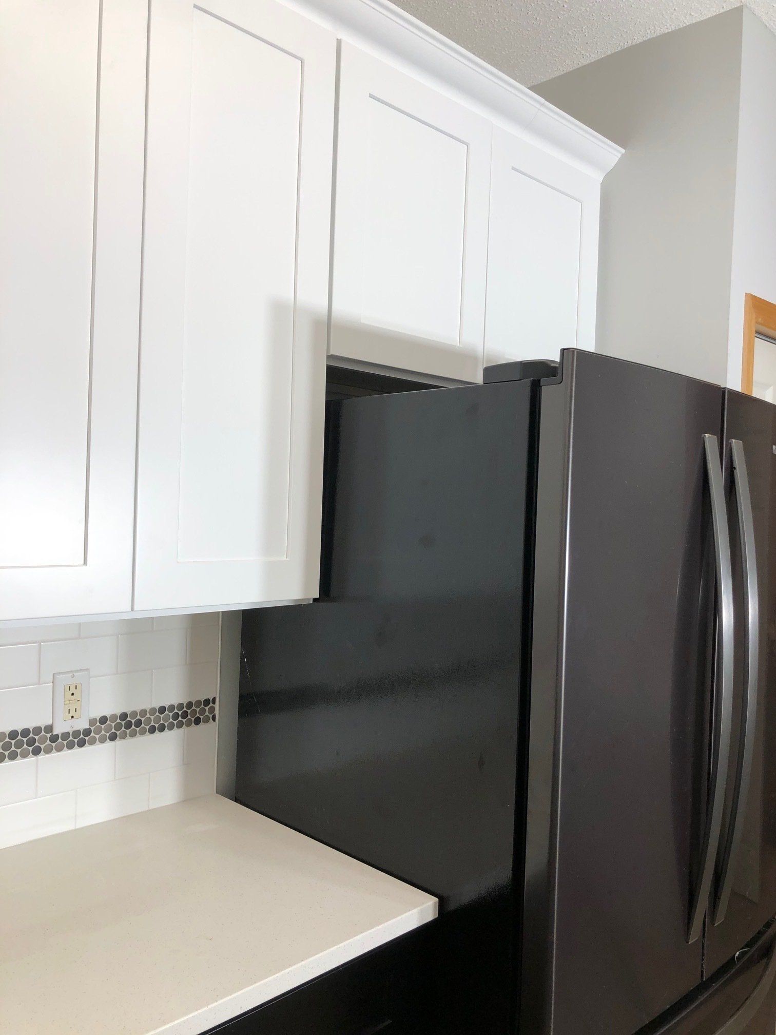 A kitchen with white cabinets and a black refrigerator
