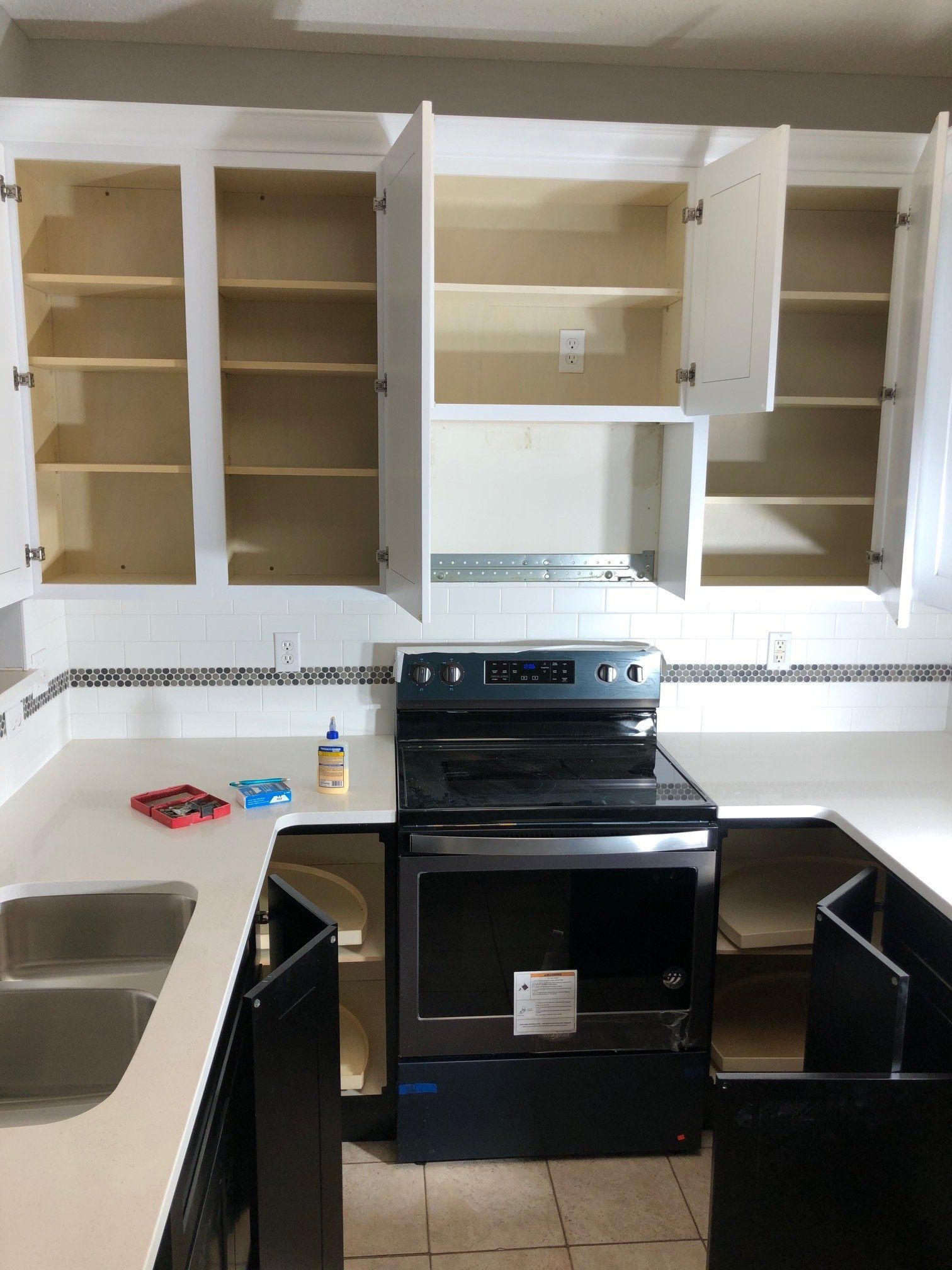 A kitchen with empty cabinets and a stove and sink