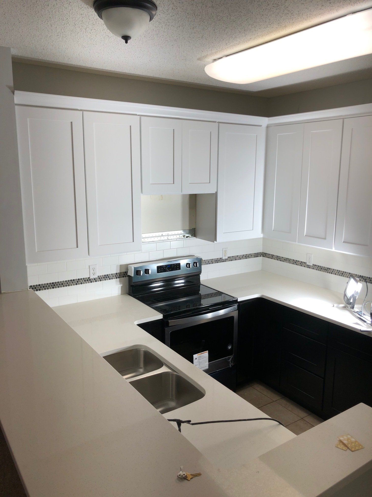 A kitchen with white cabinets and a stove and sink