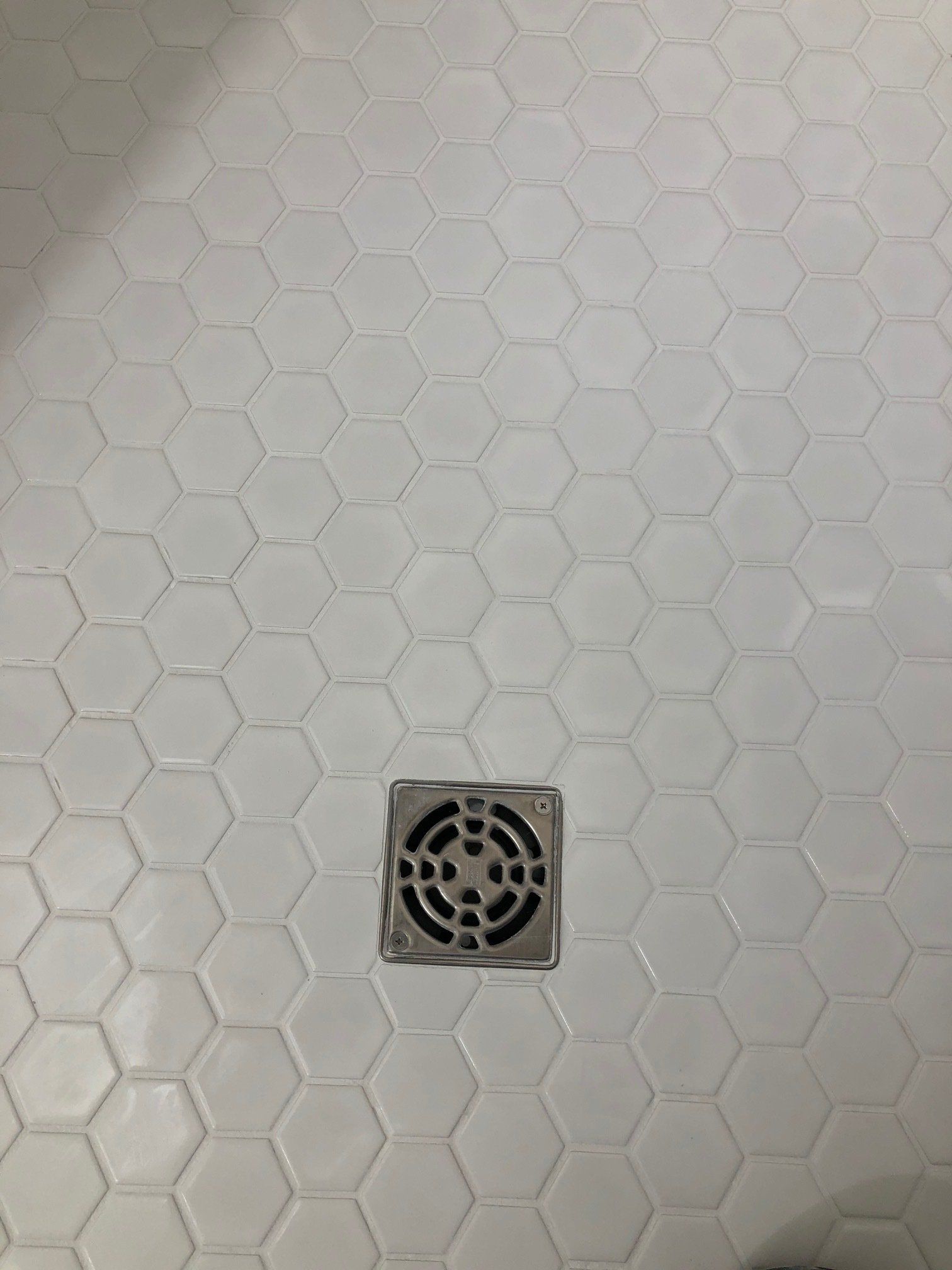 A close up of a shower floor with a drain on it.