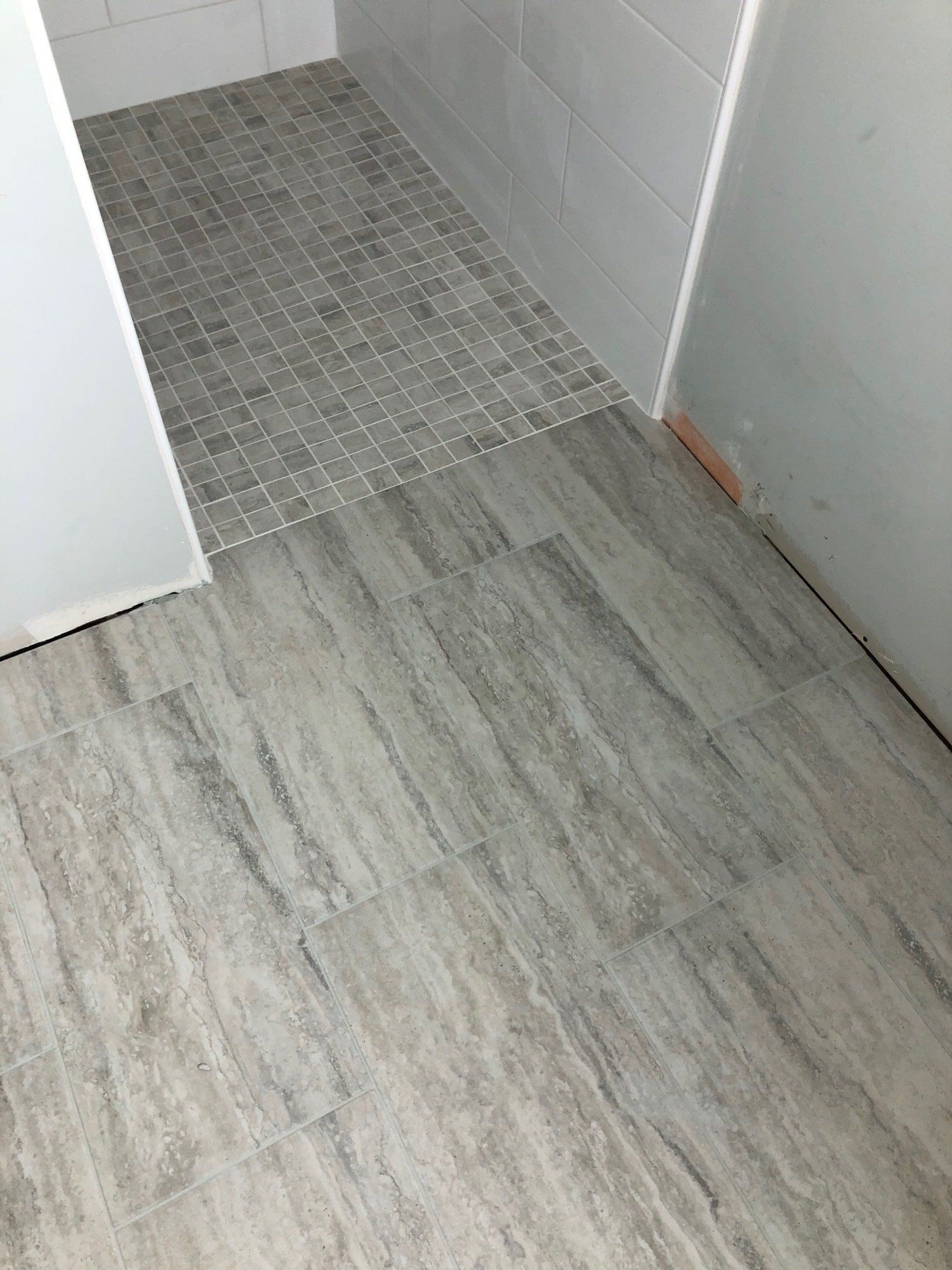 A bathroom with a tiled floor and a walk in shower.