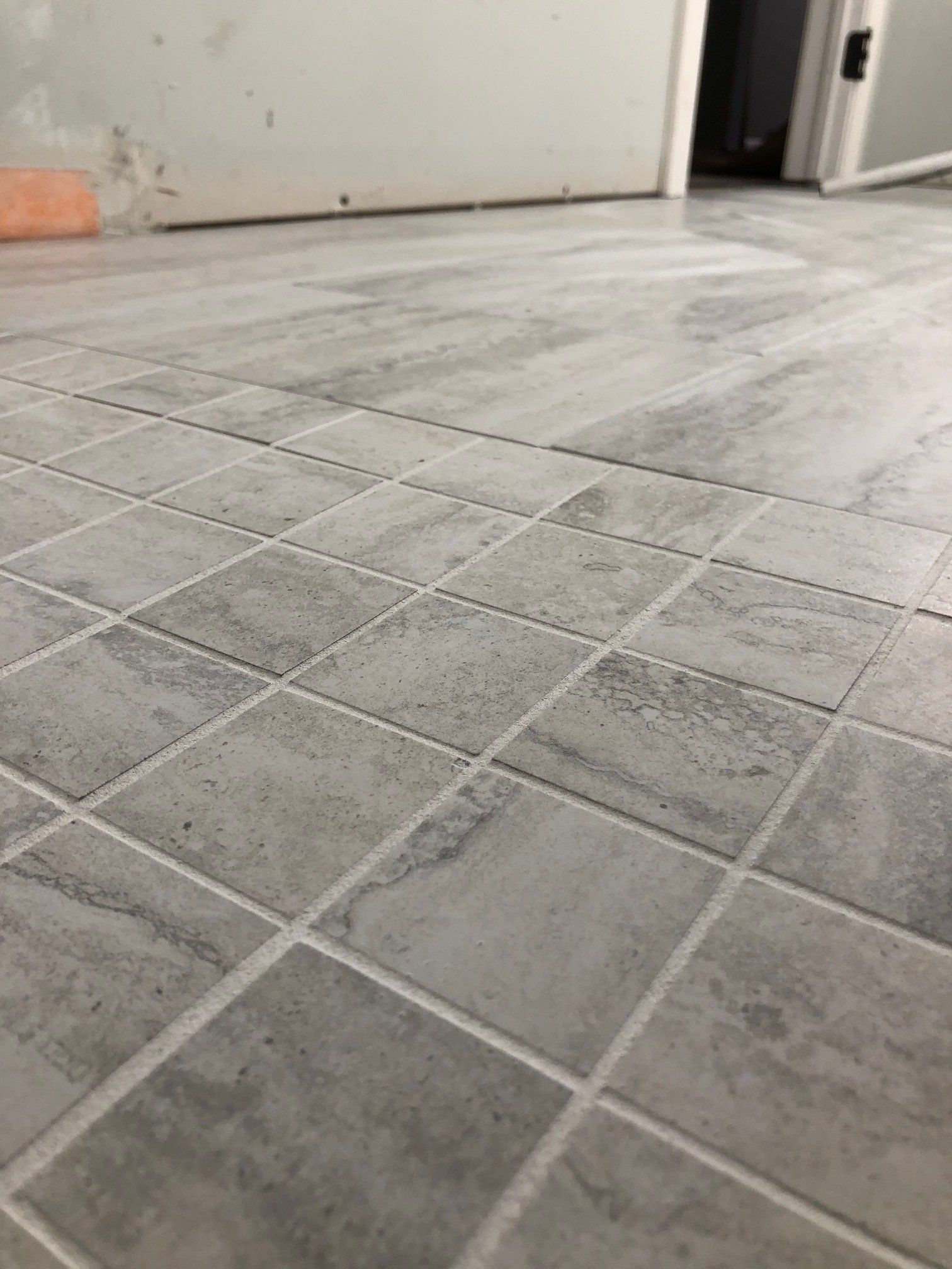 A close up of a tiled floor with a door in the background.