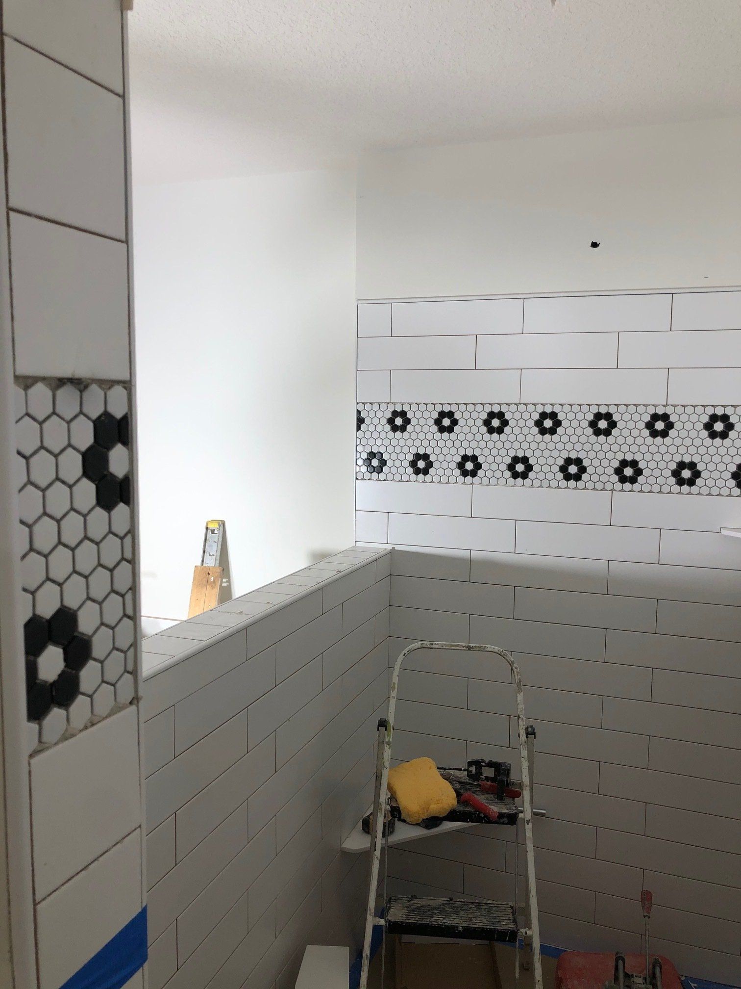 A bathroom with white tiles and a ladder